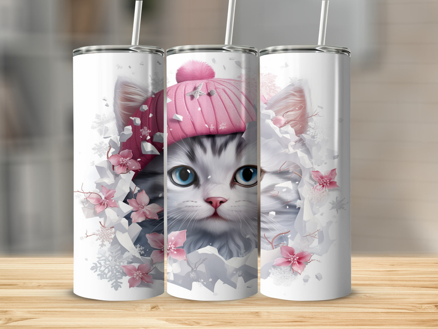 Gray and white kitten wearing a pink pom-pom hat, surrounded by snowflakes and pink flowers.