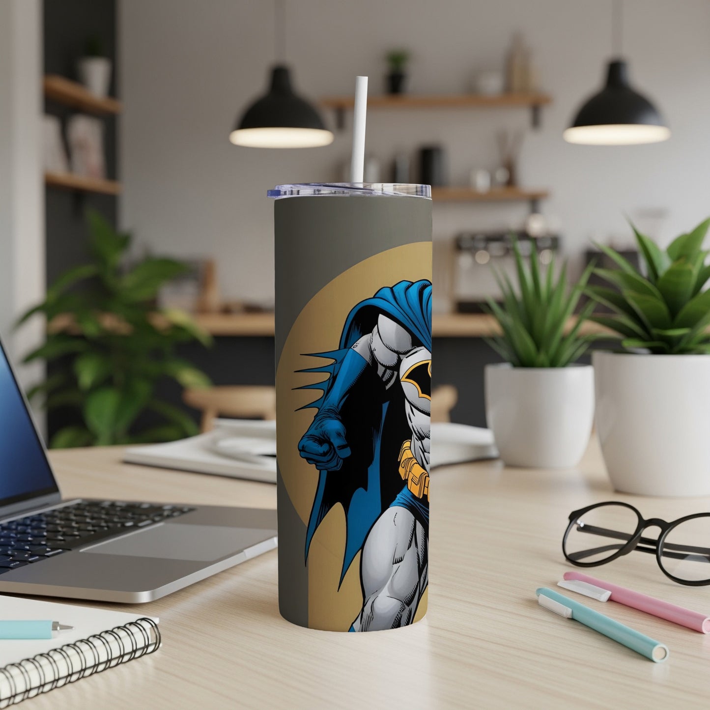 Batman illustration on a gray tumbler with a straw, on a desk.