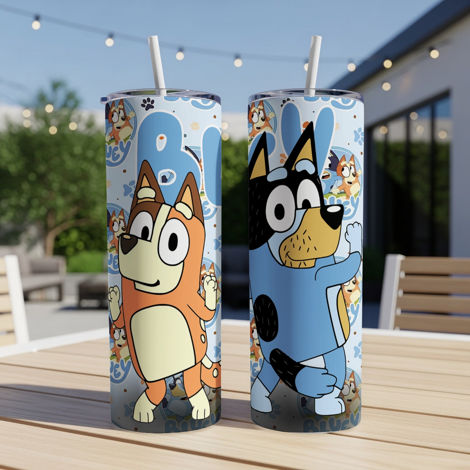 Two Bluey character tumblers with lids and straws on a wooden table.