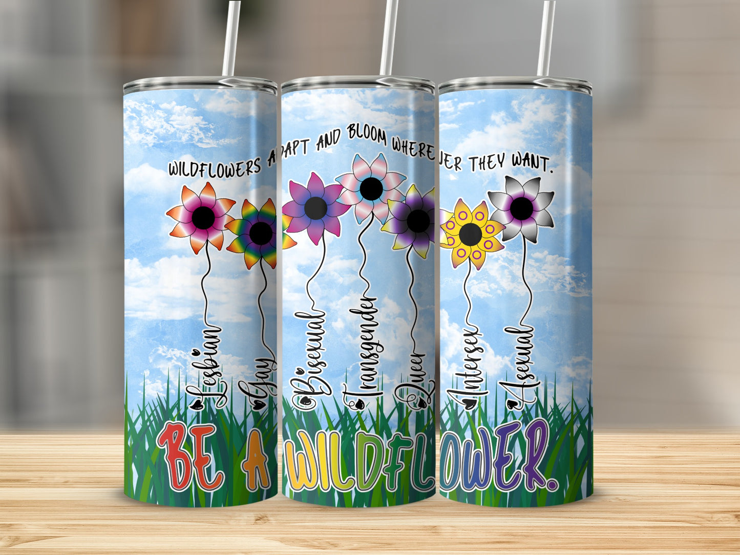 Three tumblers with rainbow flowers and LGBTQ+ pride flags, saying "Be a Wildflower."