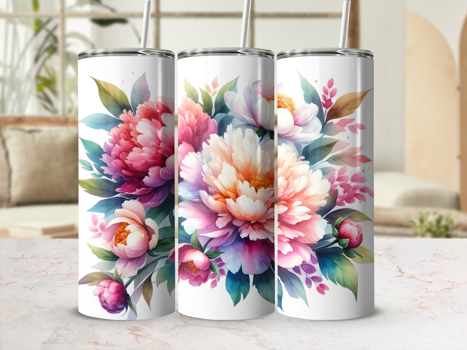 Three floral-patterned tumblers with straws sit on a marbled surface.