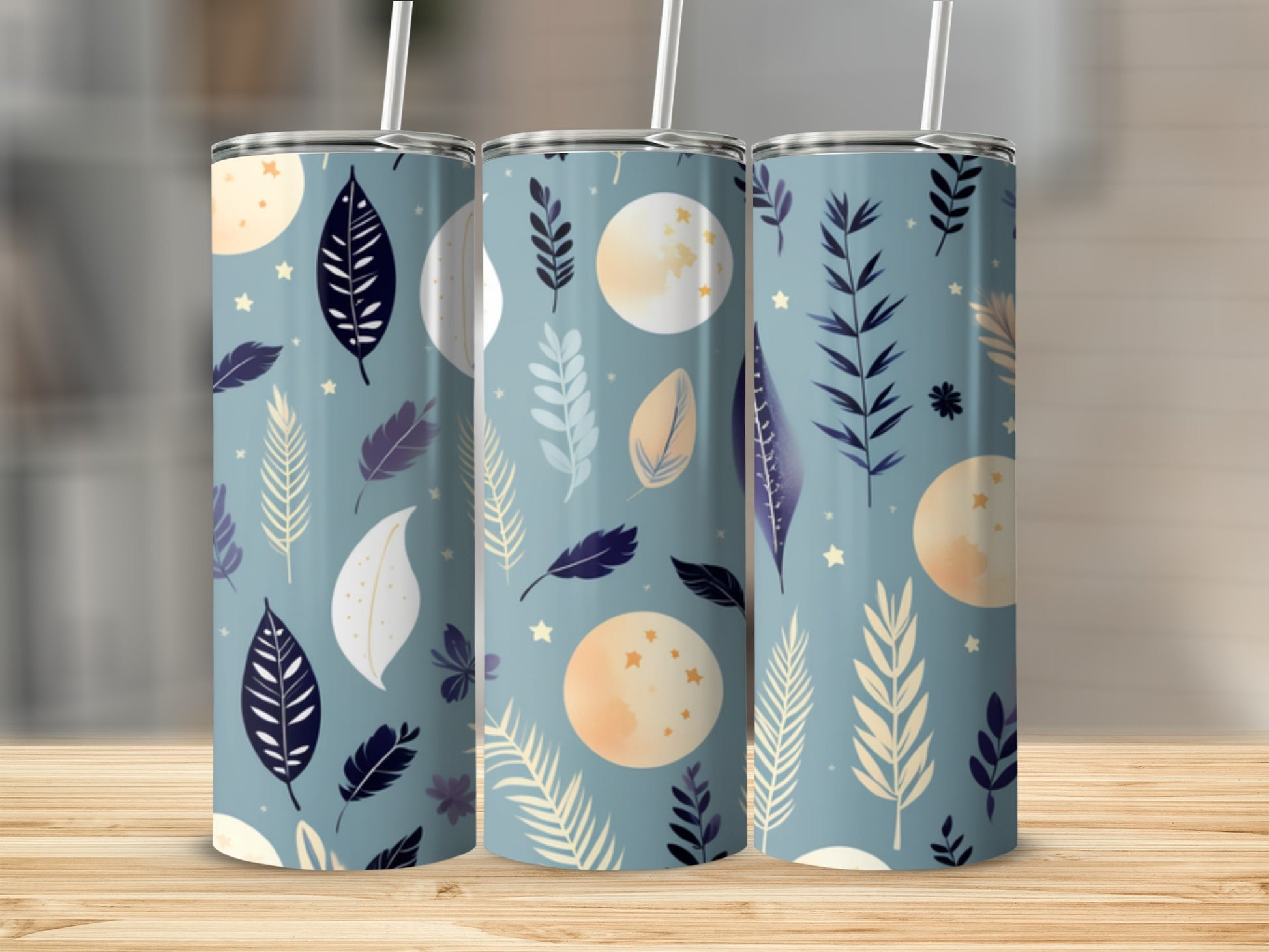 Three tumblers with a celestial moon and feather pattern on a wooden surface.