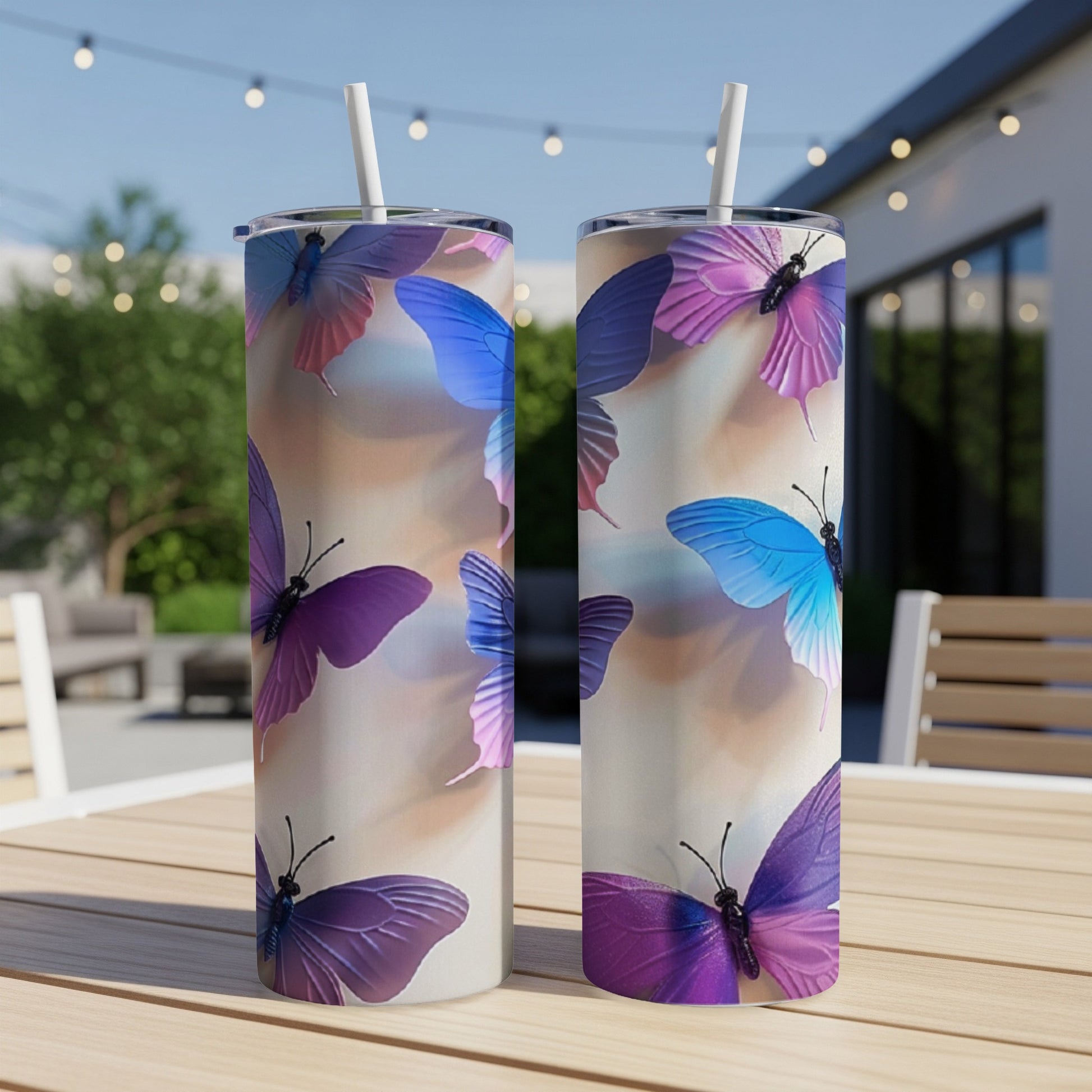 Two tumblers with purple and blue butterflies on a table outdoors.
