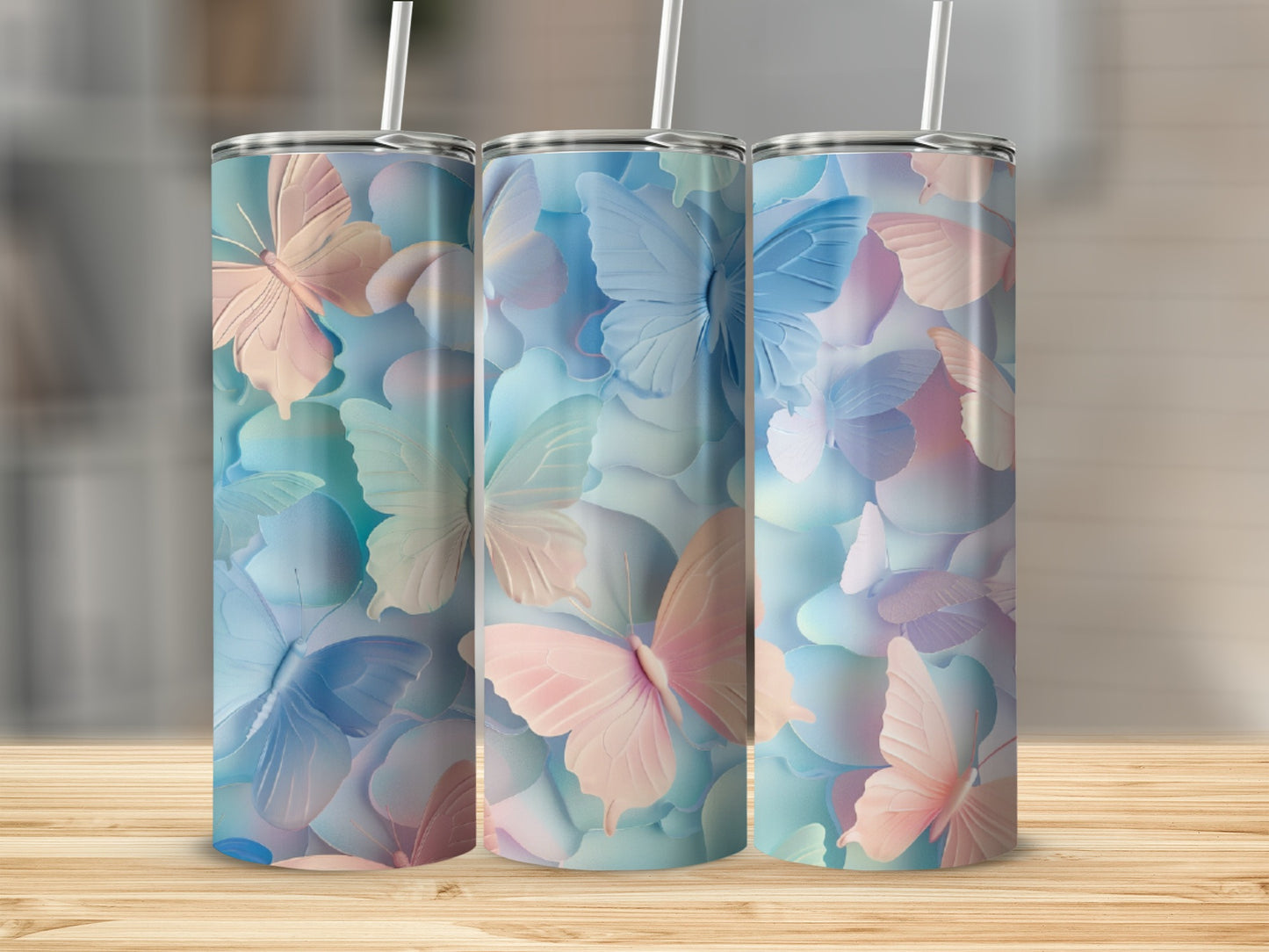 Three pastel butterfly tumblers with straws on a wooden surface.