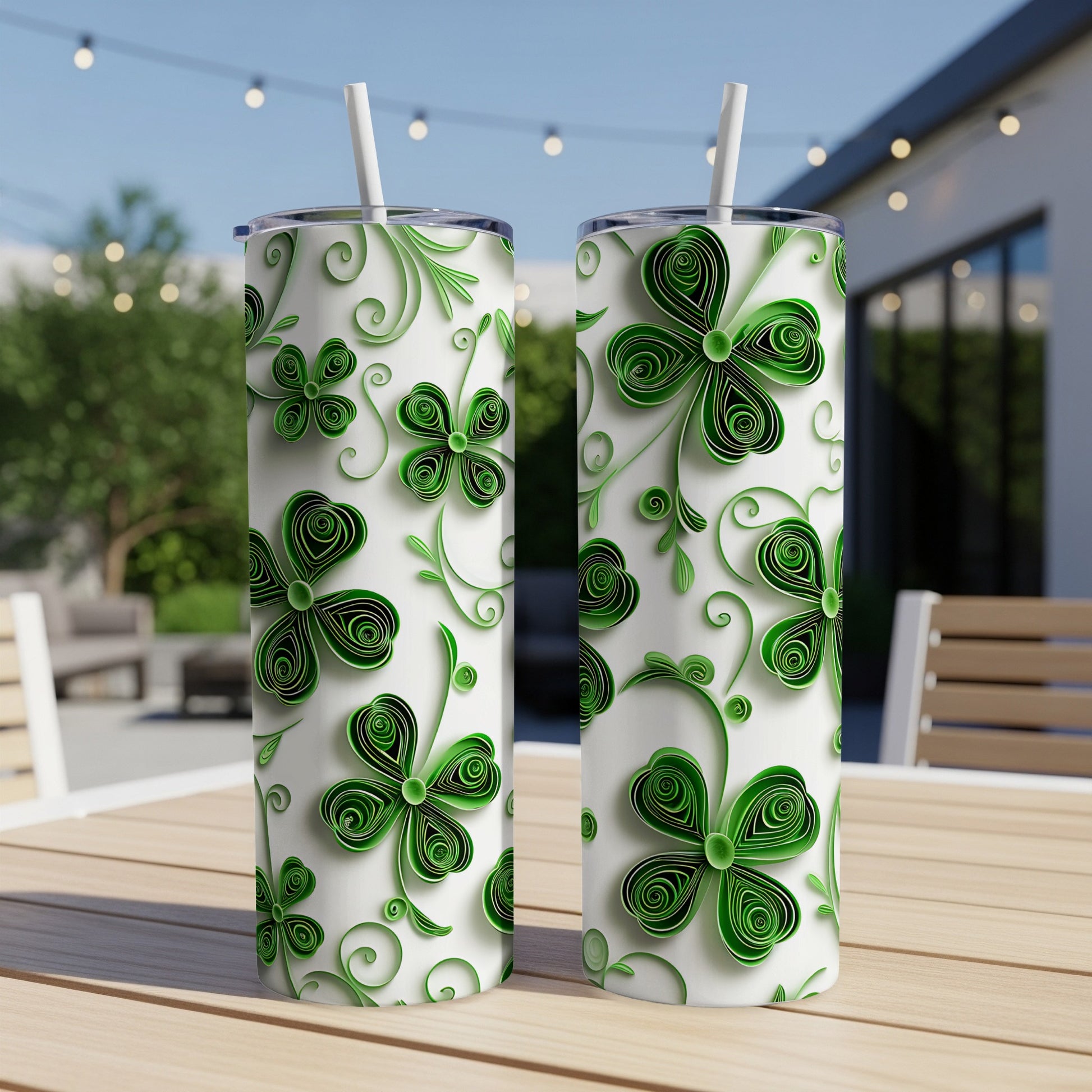 Two green shamrock patterned tumblers with straws on a wooden table.