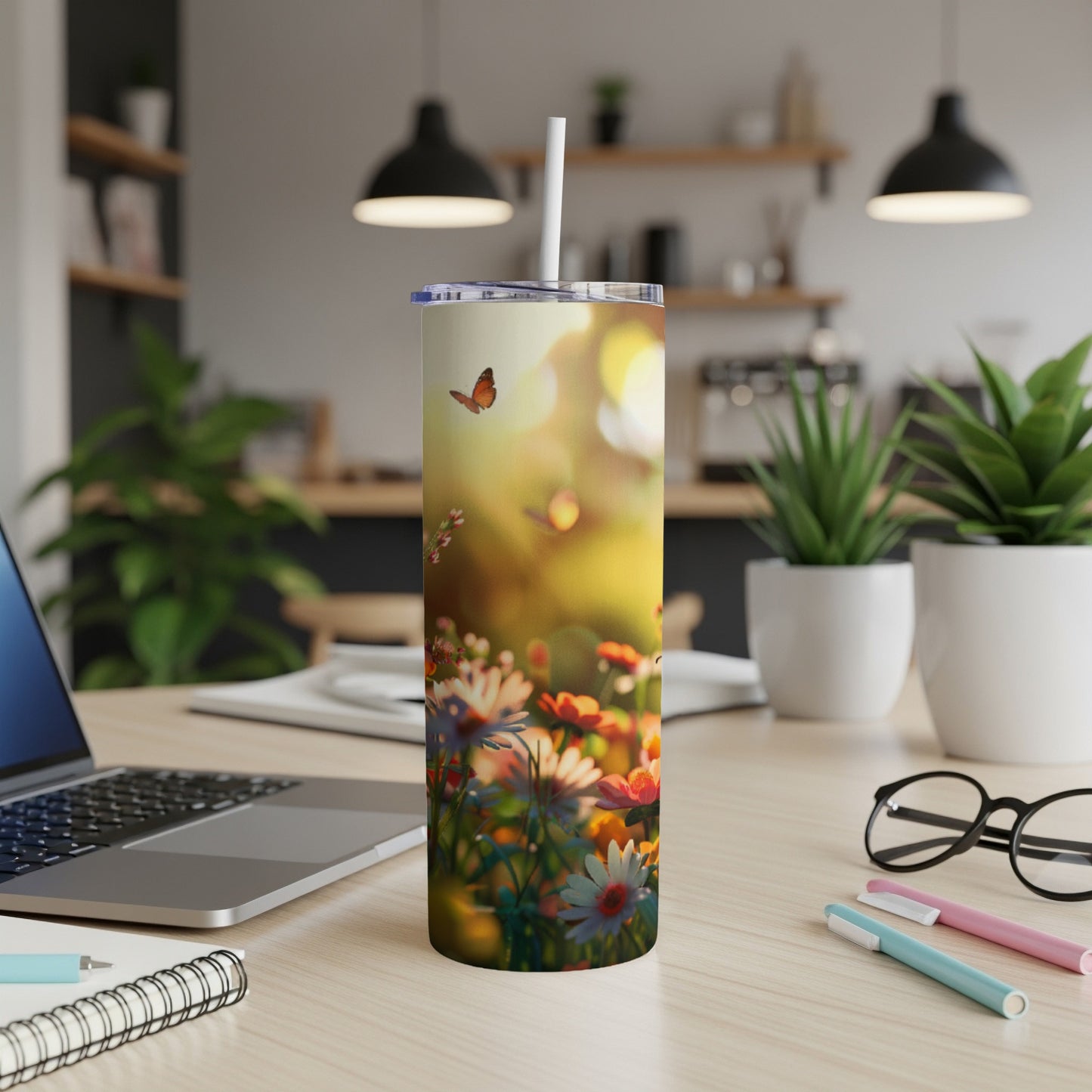 Tumbler with colorful flowers and a butterfly, resting on a desk.