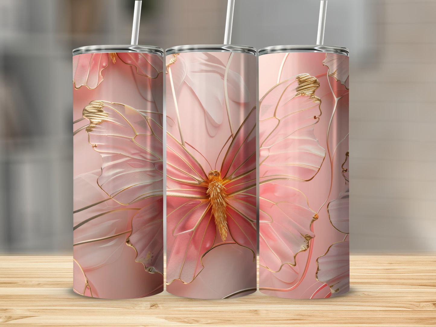 Three pink tumblers with a golden butterfly design on a wooden surface.