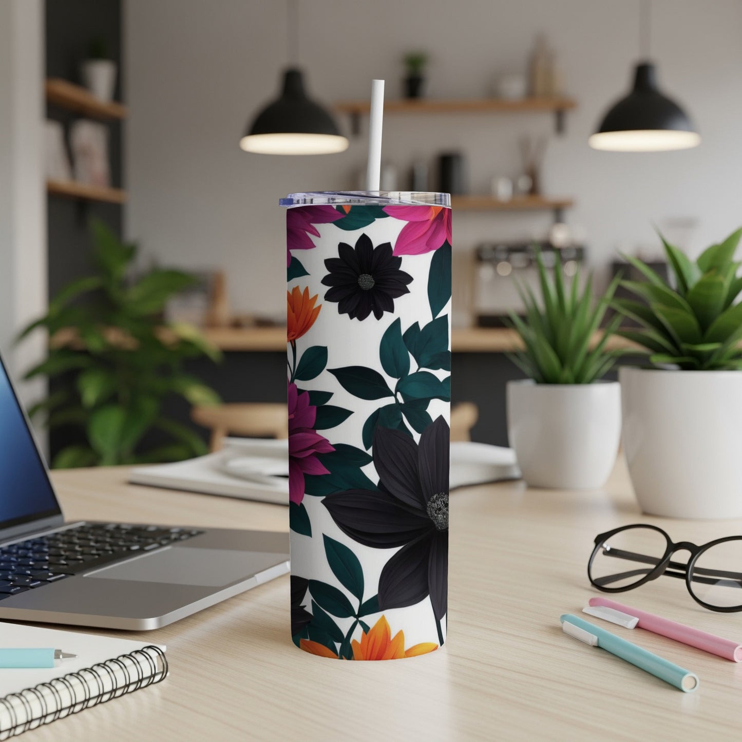 Floral pattern tumbler with a straw on a desk with a laptop.