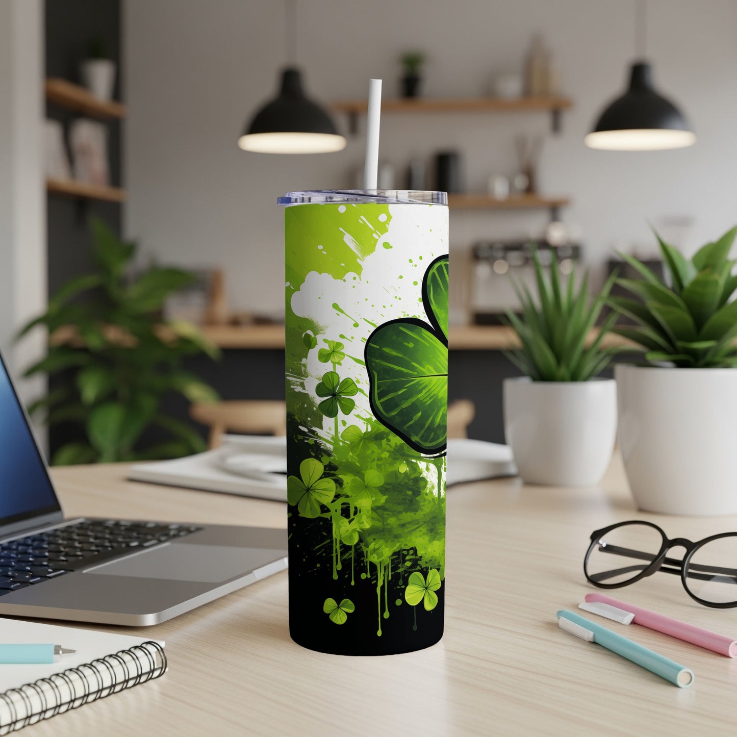 Green clover tumbler with white straw on desk next to laptop.
