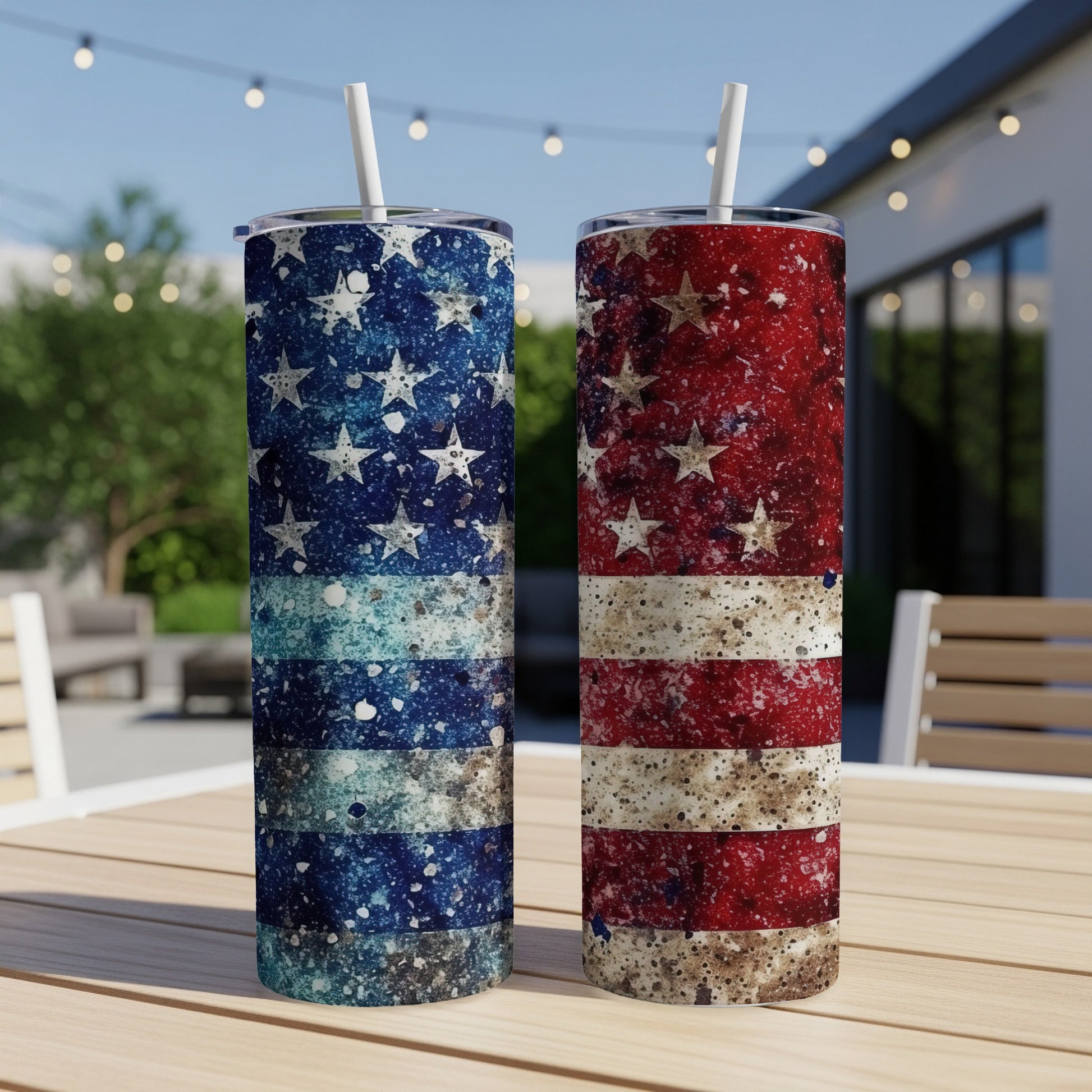 Two American flag tumblers with straws on a table outdoors.