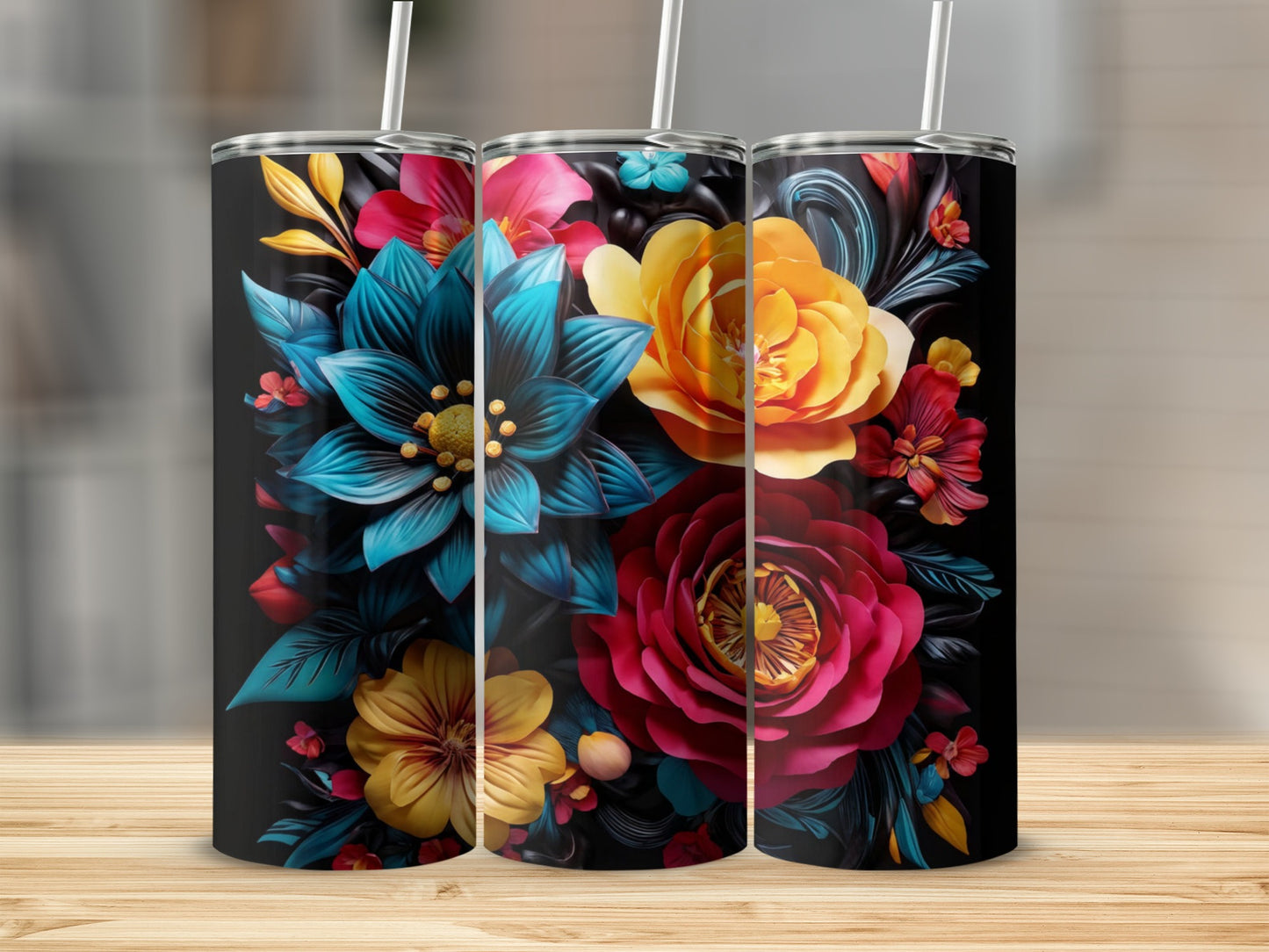 Three tumblers with vibrant floral designs on a wooden surface.
