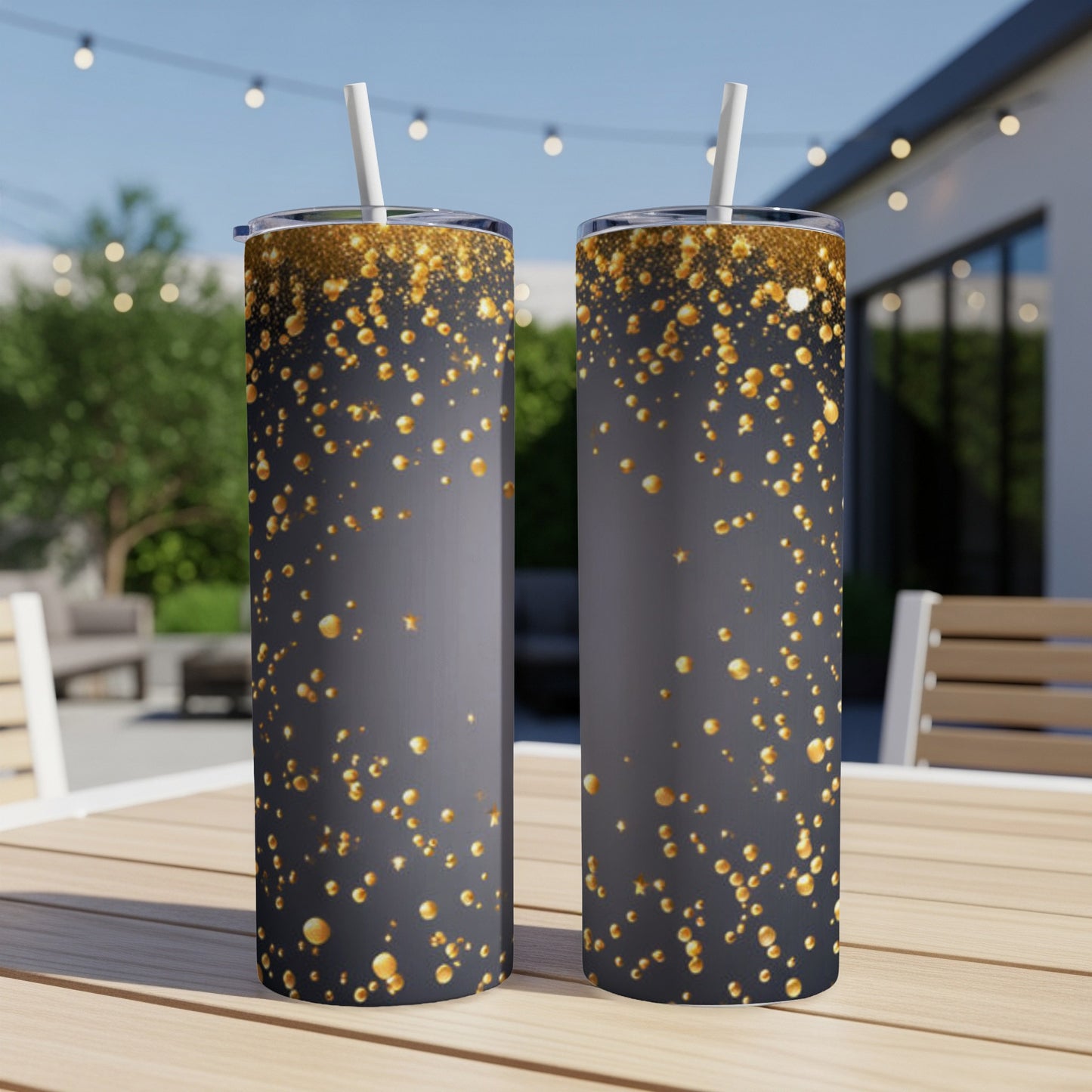 Two dark grey tumblers with gold glitter confetti and straws.
