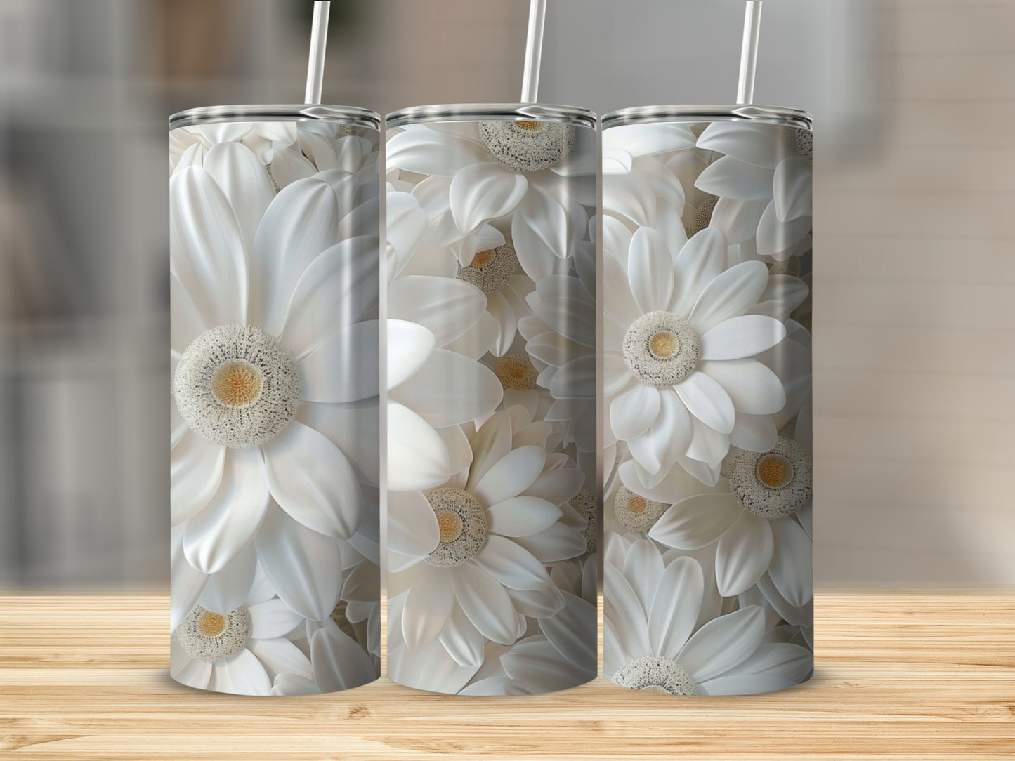 Three white floral tumblers with straws on a wooden surface.