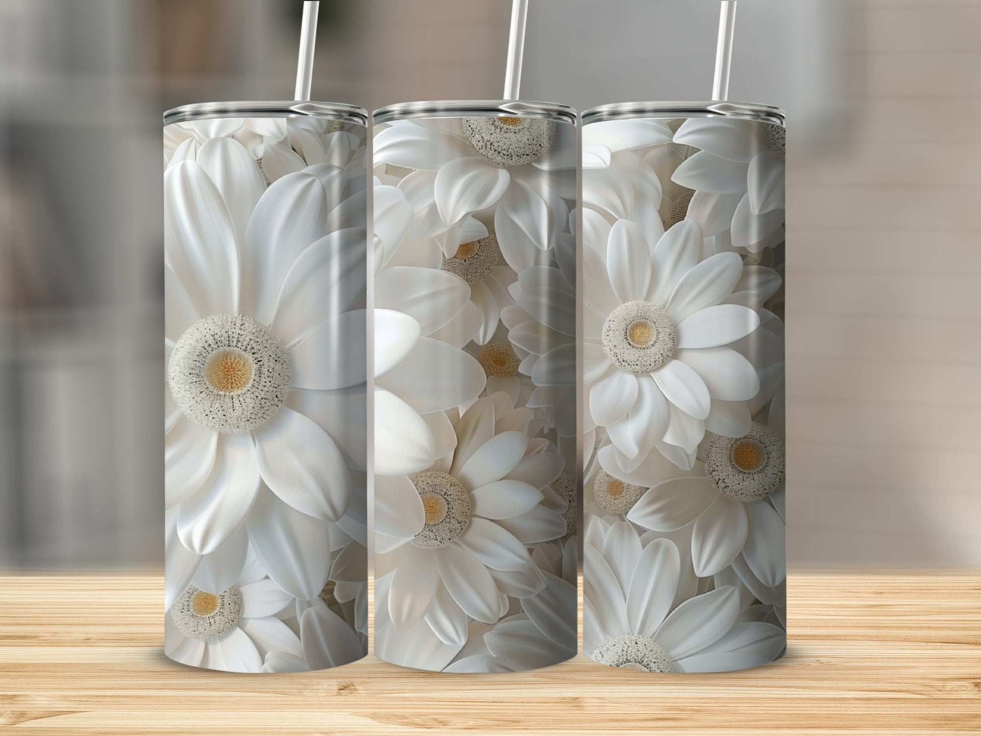 Three white floral tumblers with straws on a wooden surface.