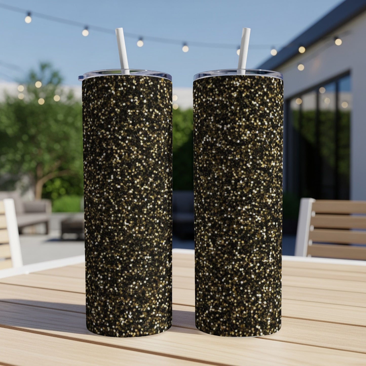 Two tall, slim tumblers with a gold and black glitter pattern, outdoors.