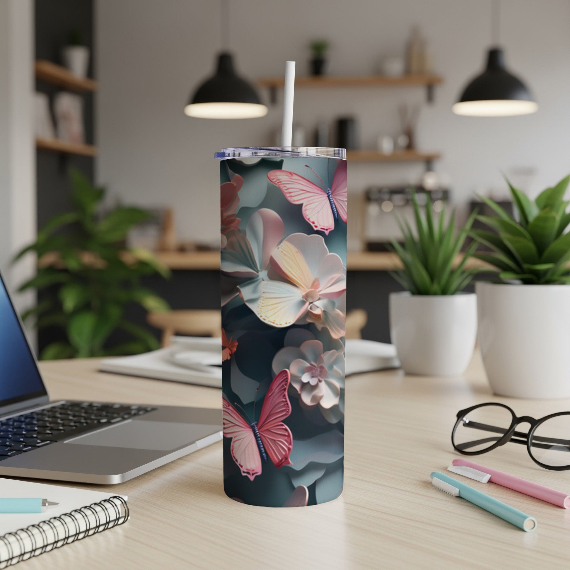 Tumbler with pink butterflies and floral pattern on a desk.