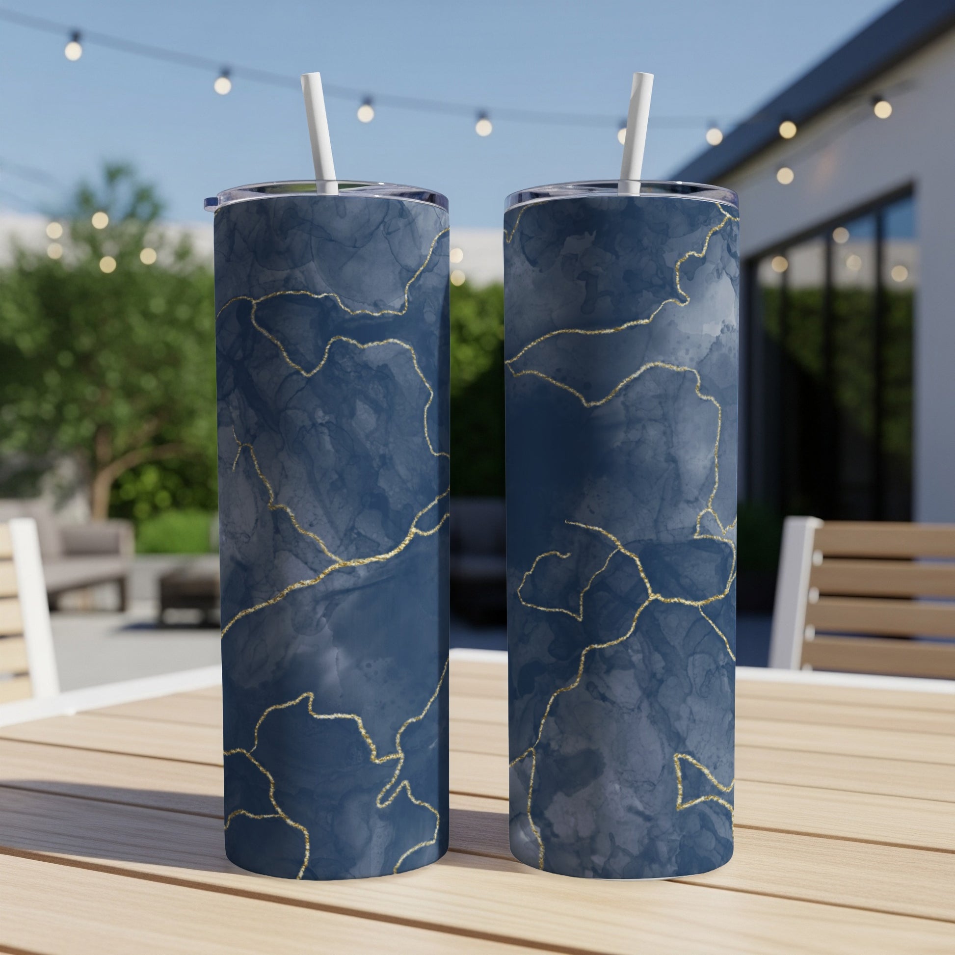 Two dark blue tumblers with gold marbled patterns on a wooden table.