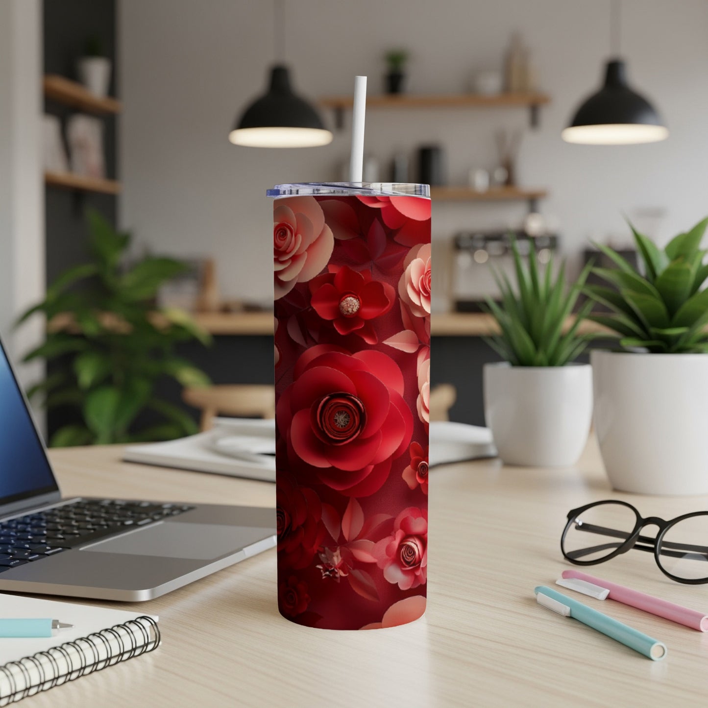 Red floral tumbler with straw on a desk with a laptop.