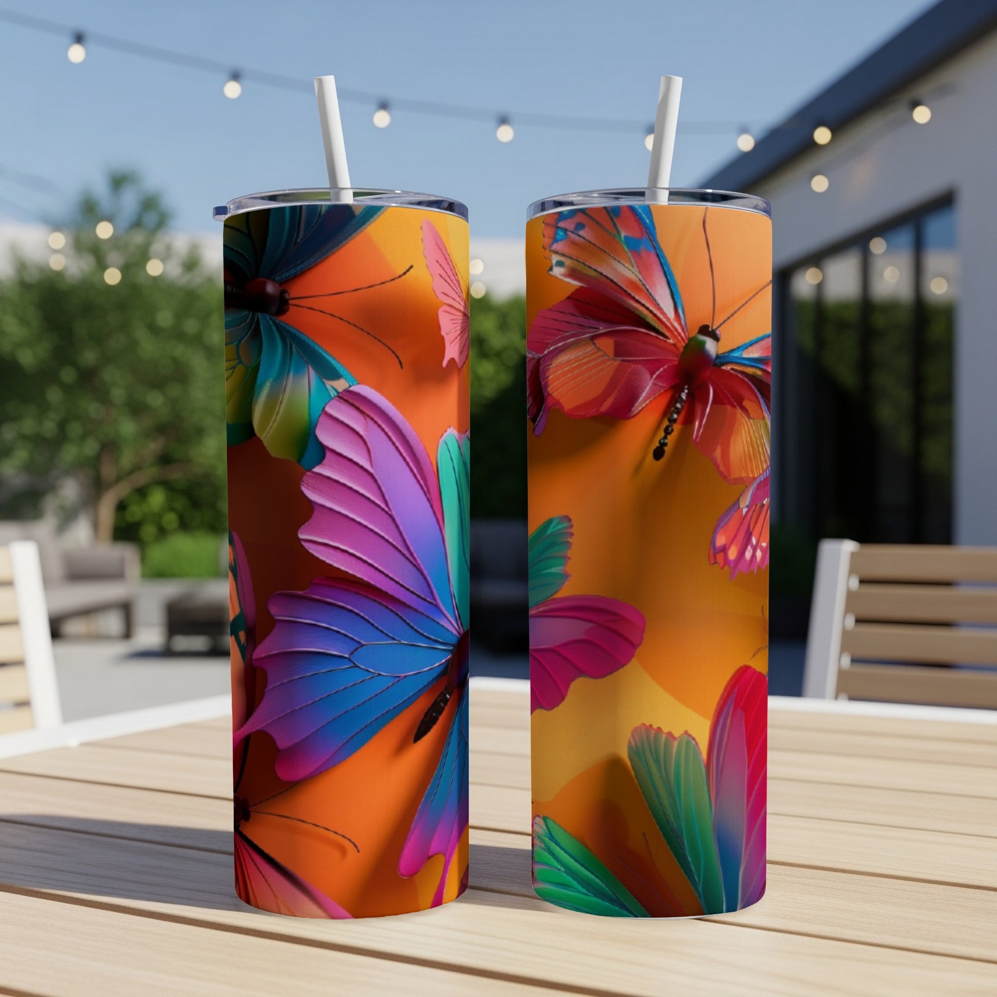 Two tumblers with colorful butterfly and floral designs on an outdoor table.
