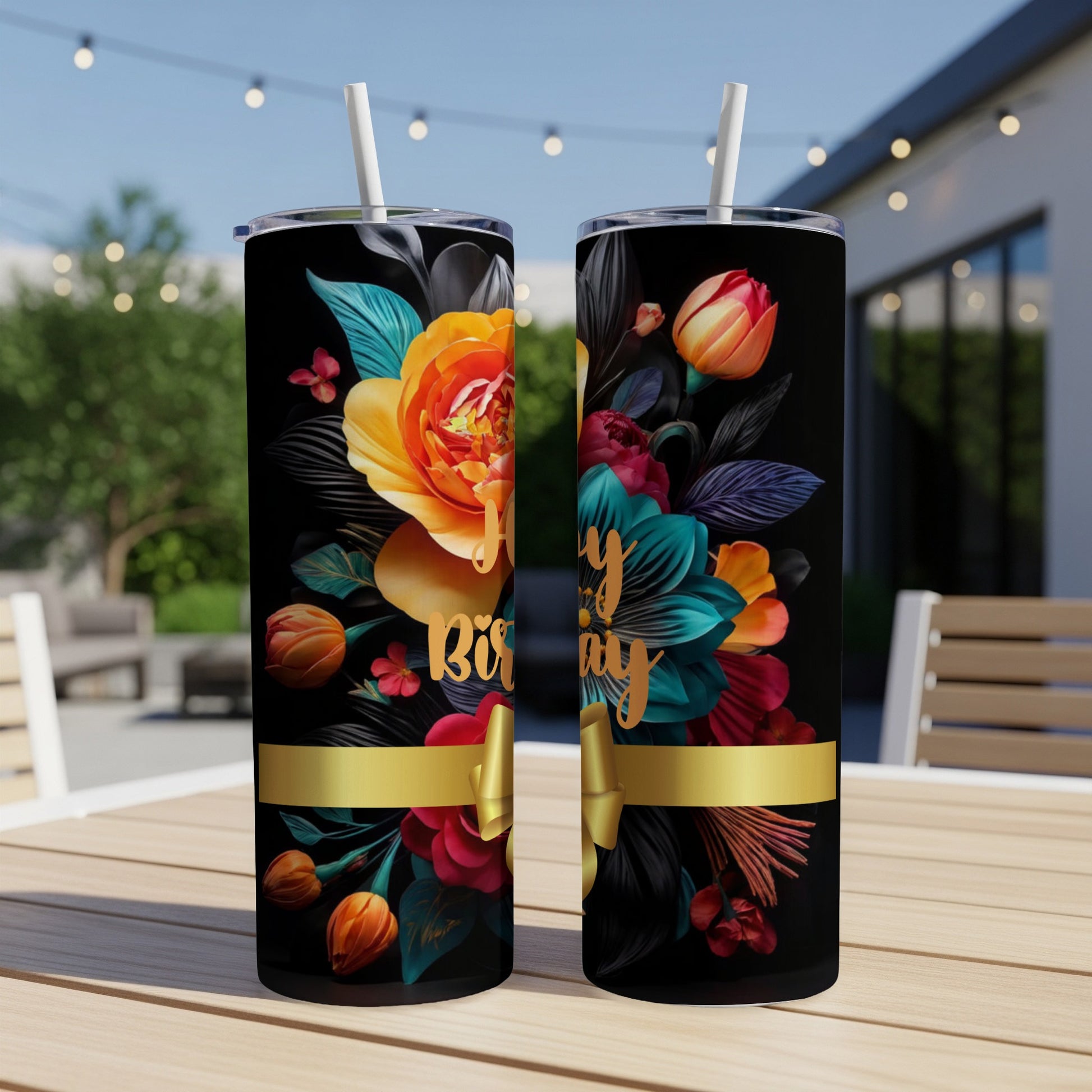 Floral "Happy Birthday" tumbler with gold ribbon and straw on a table.