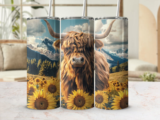 Highland cow in a field of sunflowers with mountains in the background.