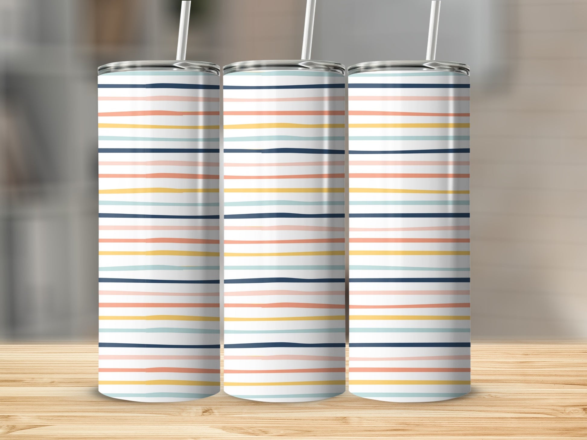Three tumblers with colorful horizontal stripes stand on a wooden surface.