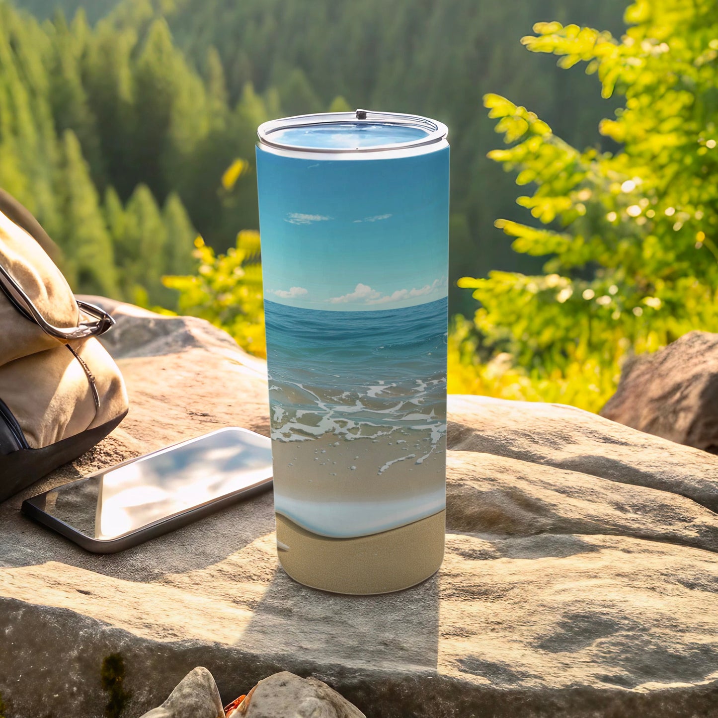 Beach scene tumbler on a rock with a backpack and phone.
