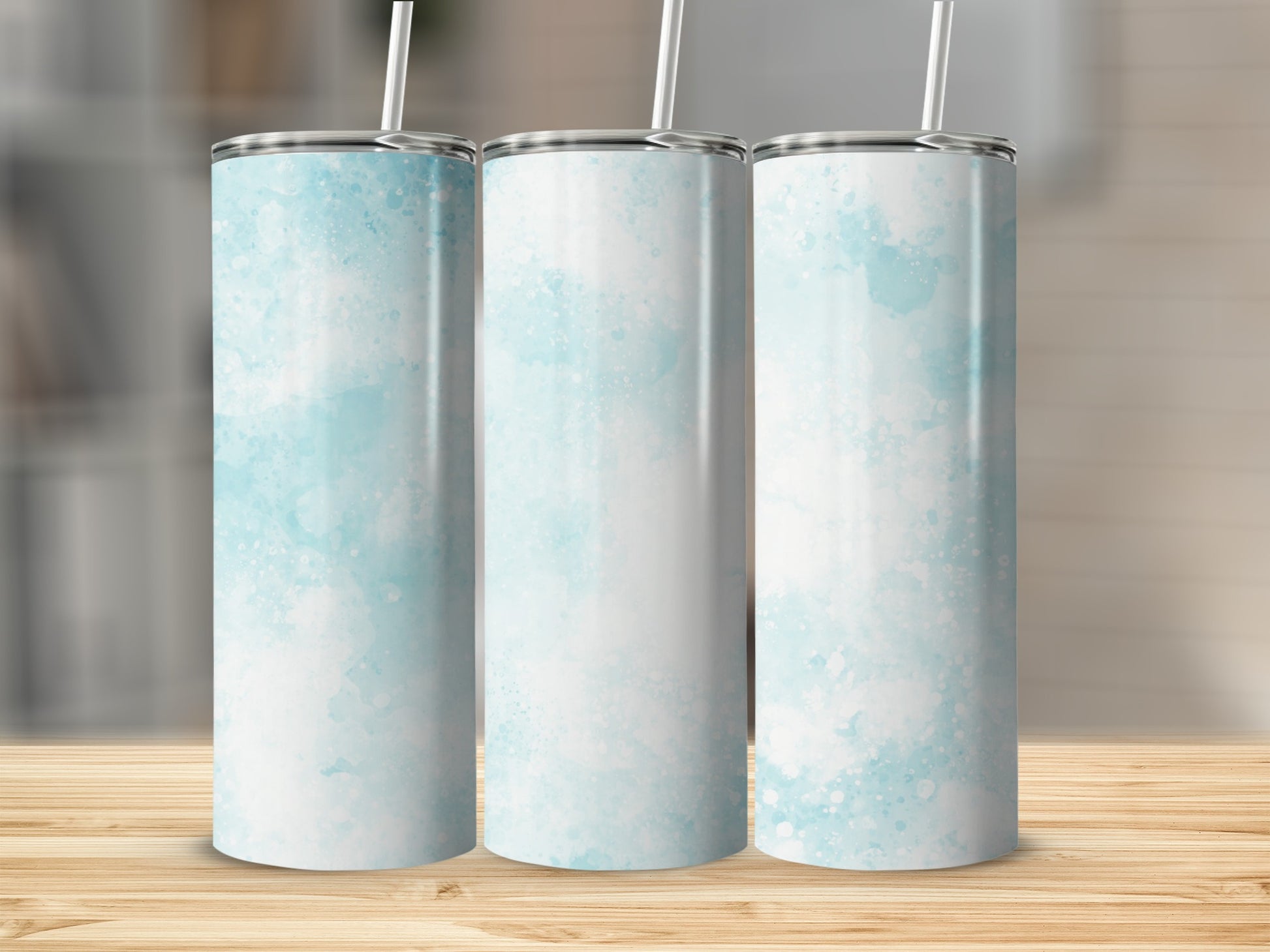 Three tumblers with a blue watercolor design on a wooden surface.