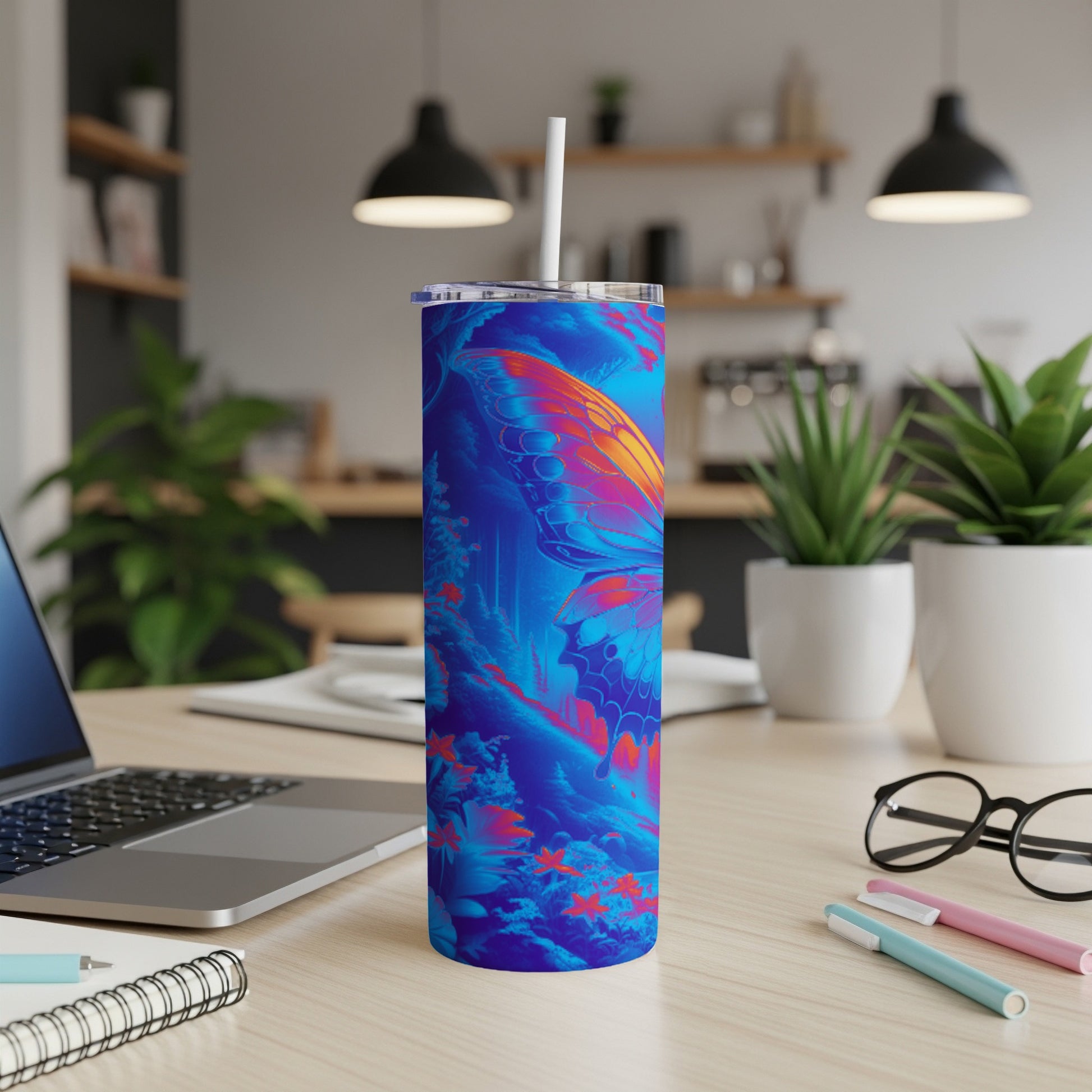 Blue tumbler with butterfly wing design, straw, and laptop on desk.