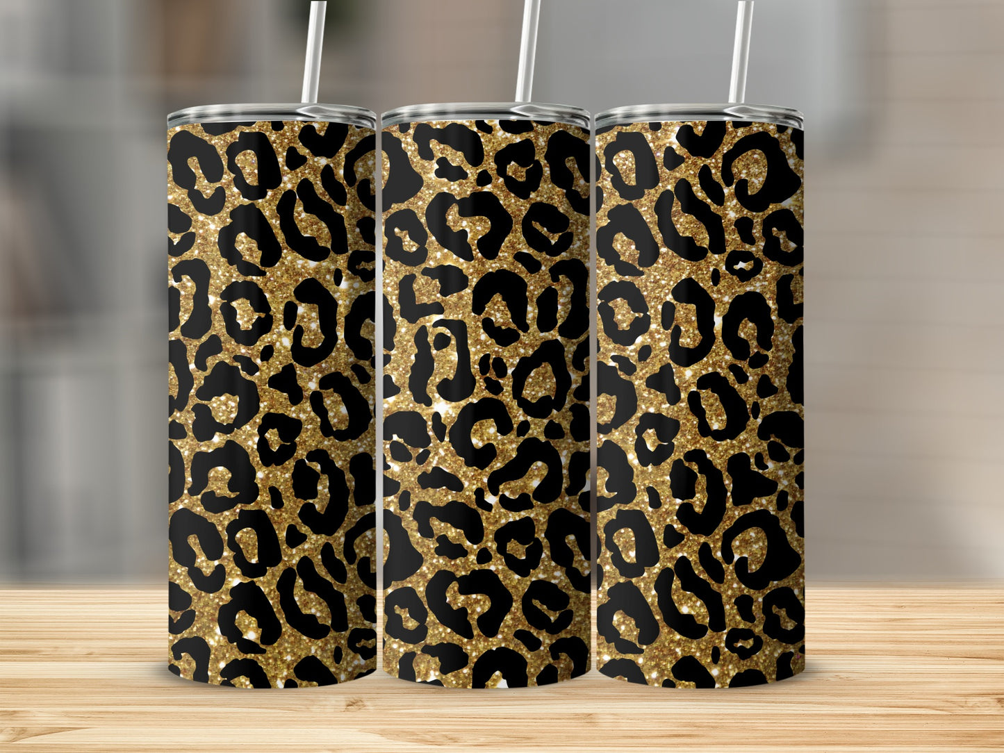 Three glittery leopard print tumblers with white straws on a wooden surface.