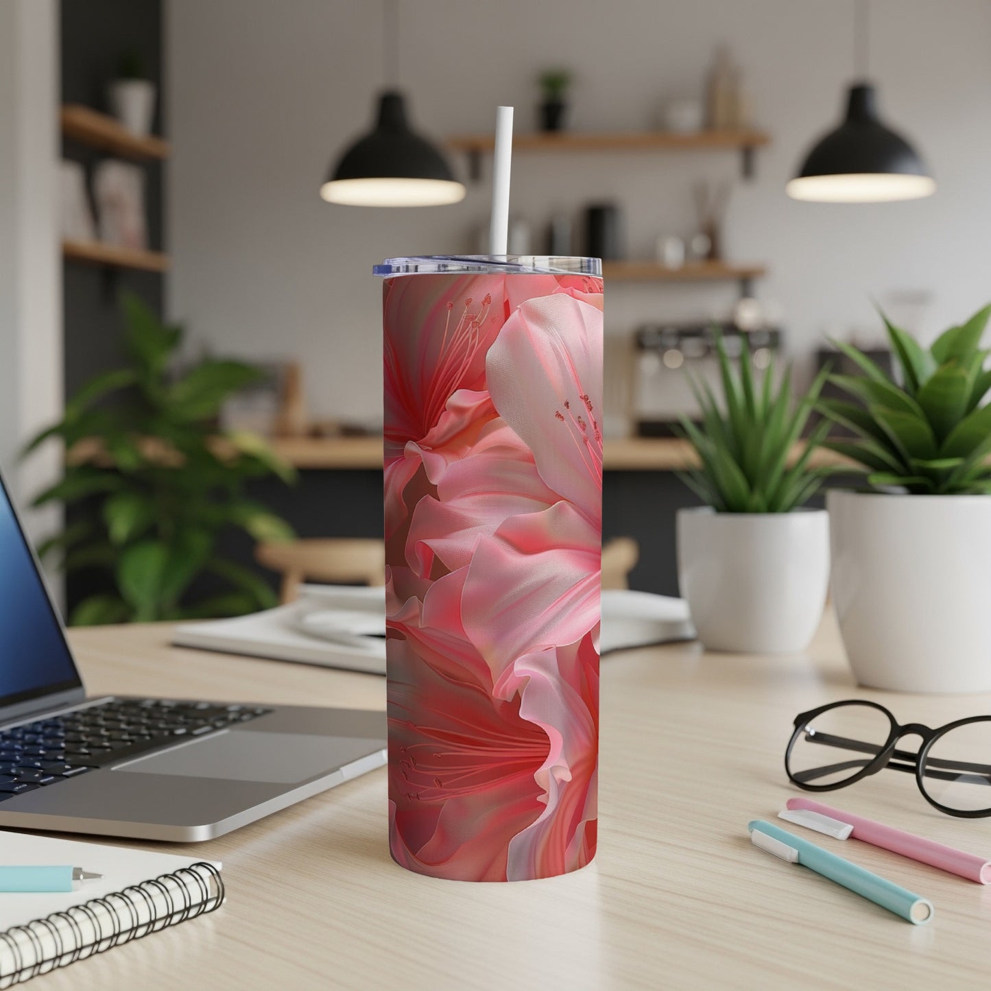Pink floral pattern on a white tumbler with straw, on a desk.