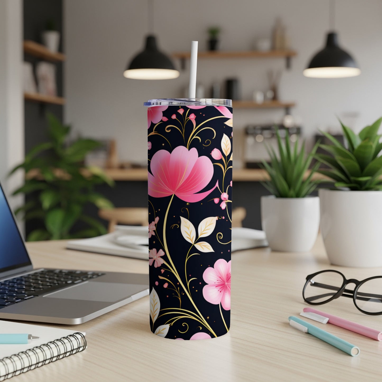 Black tumbler with pink and gold floral pattern, on a desk.
