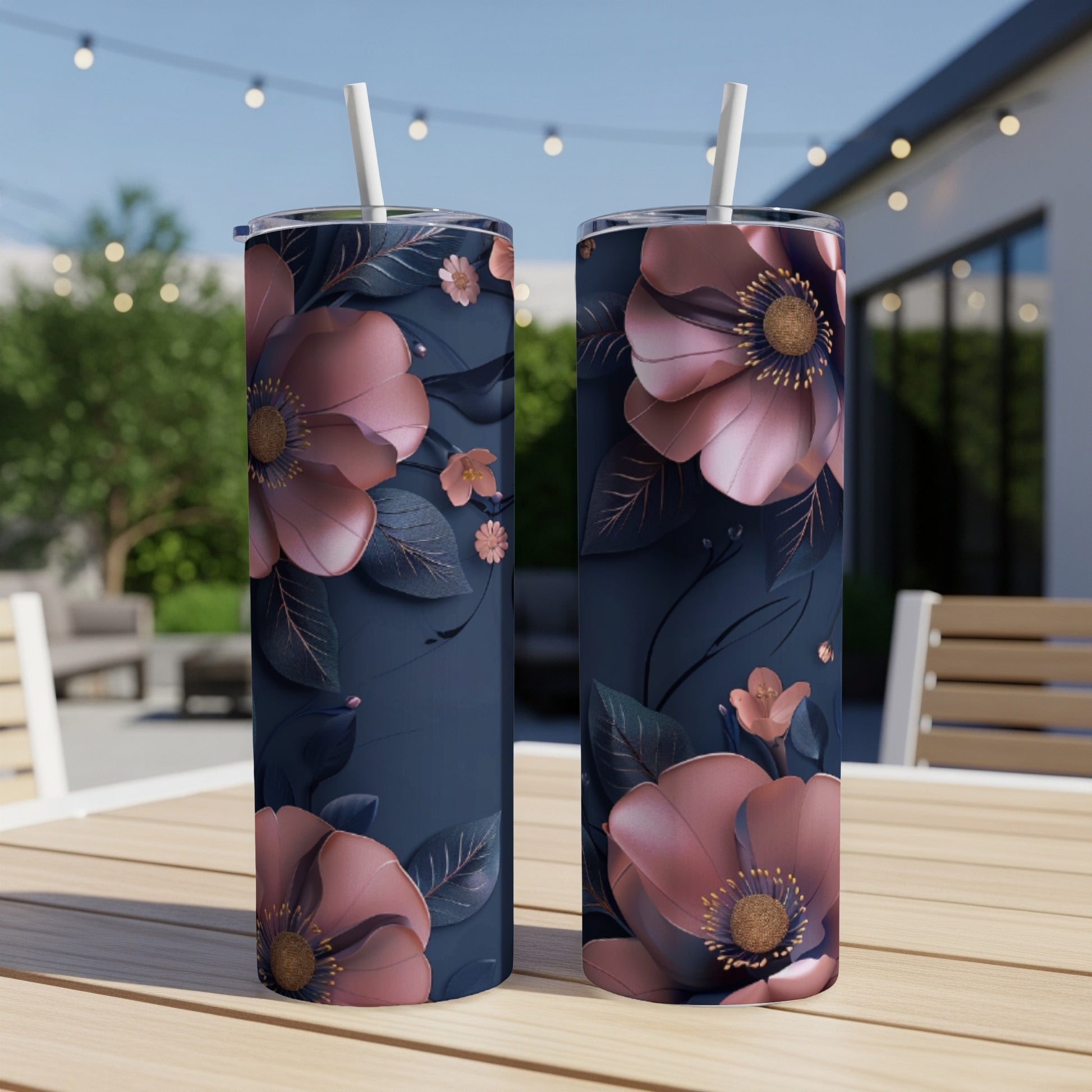 Two dark blue tumblers with large pink floral designs and straws.