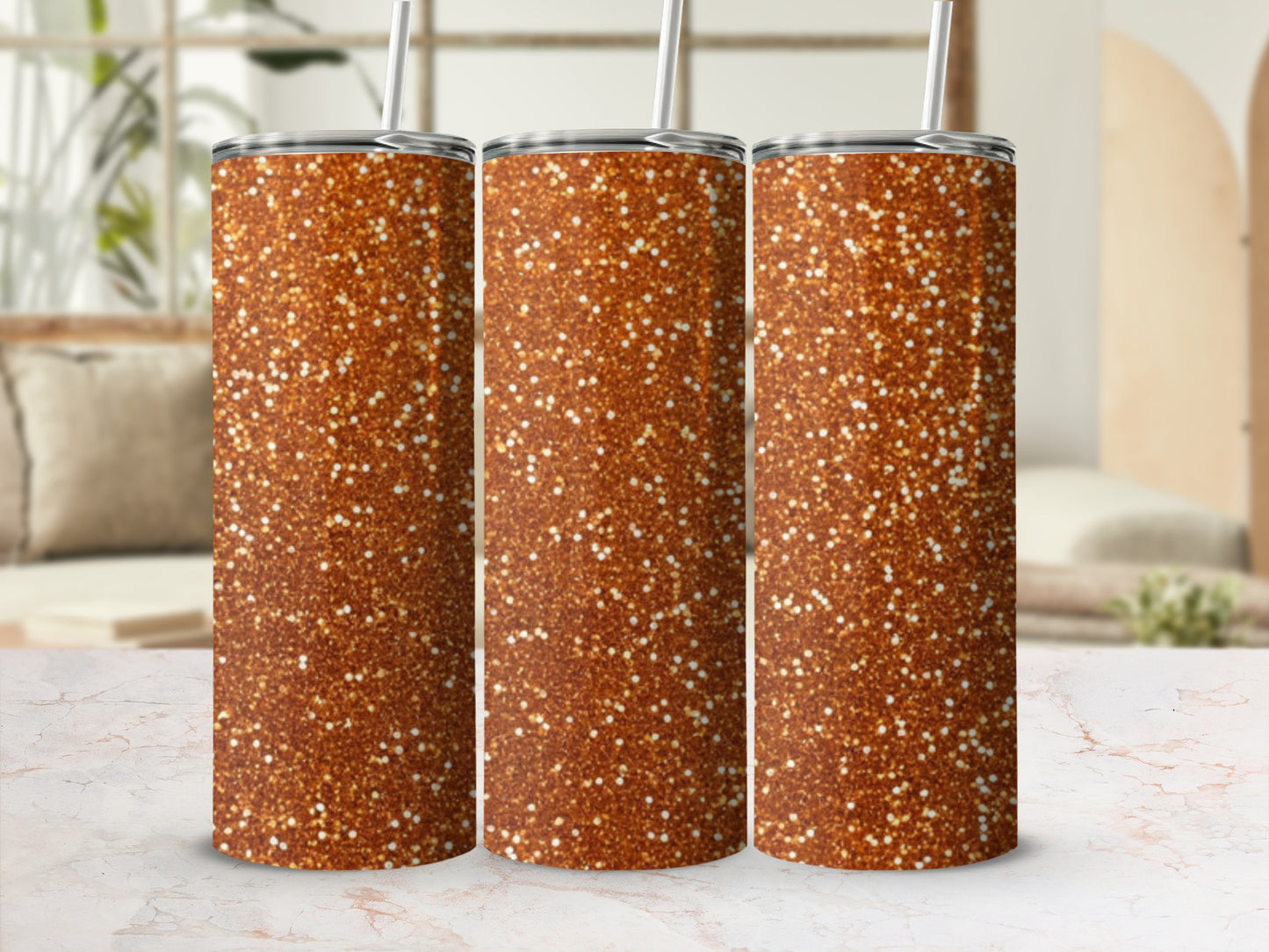 Three glitter-covered tumblers with straws on a marble surface.
