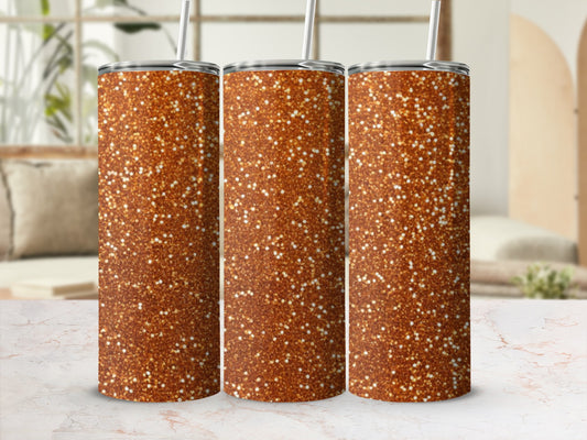 Three glitter-covered tumblers with straws on a marble surface.
