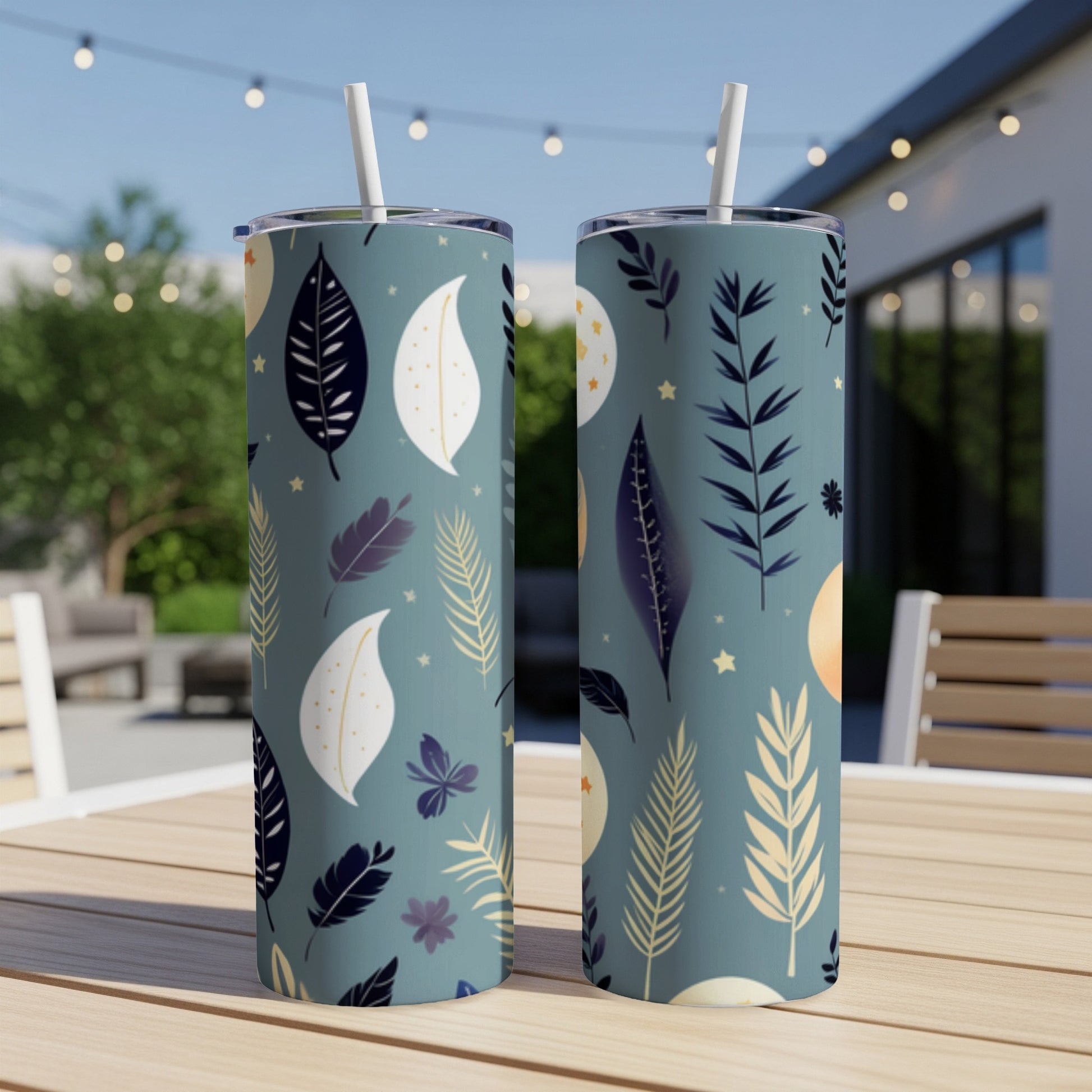 Two tumblers with a celestial leaf pattern on an outdoor table.