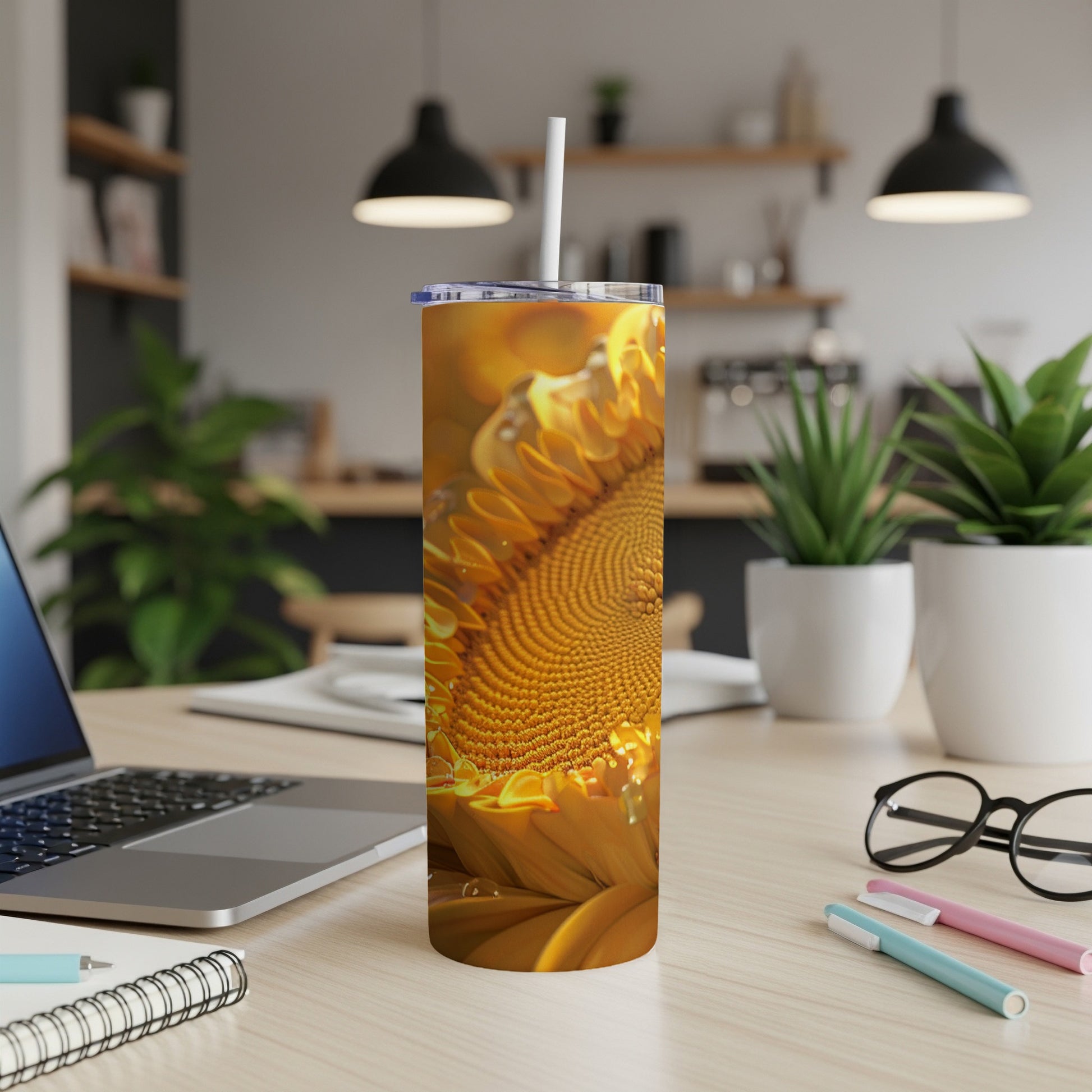 Sunflower pattern on a tumbler with a straw, on a desk with a laptop.