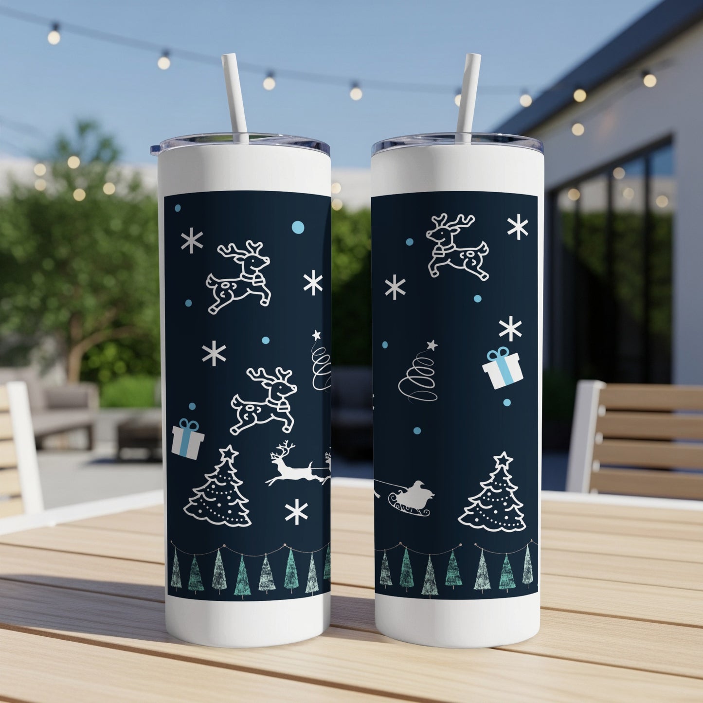 Two navy blue tumblers with a white Christmas pattern on a wooden table.