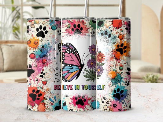 Tumbler with butterfly, paw prints, flowers, and "Believe in Yourself" text.