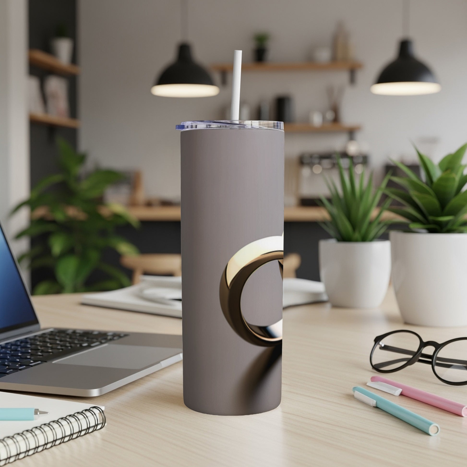 Gray tumbler with a metallic gold circle design on a desk.