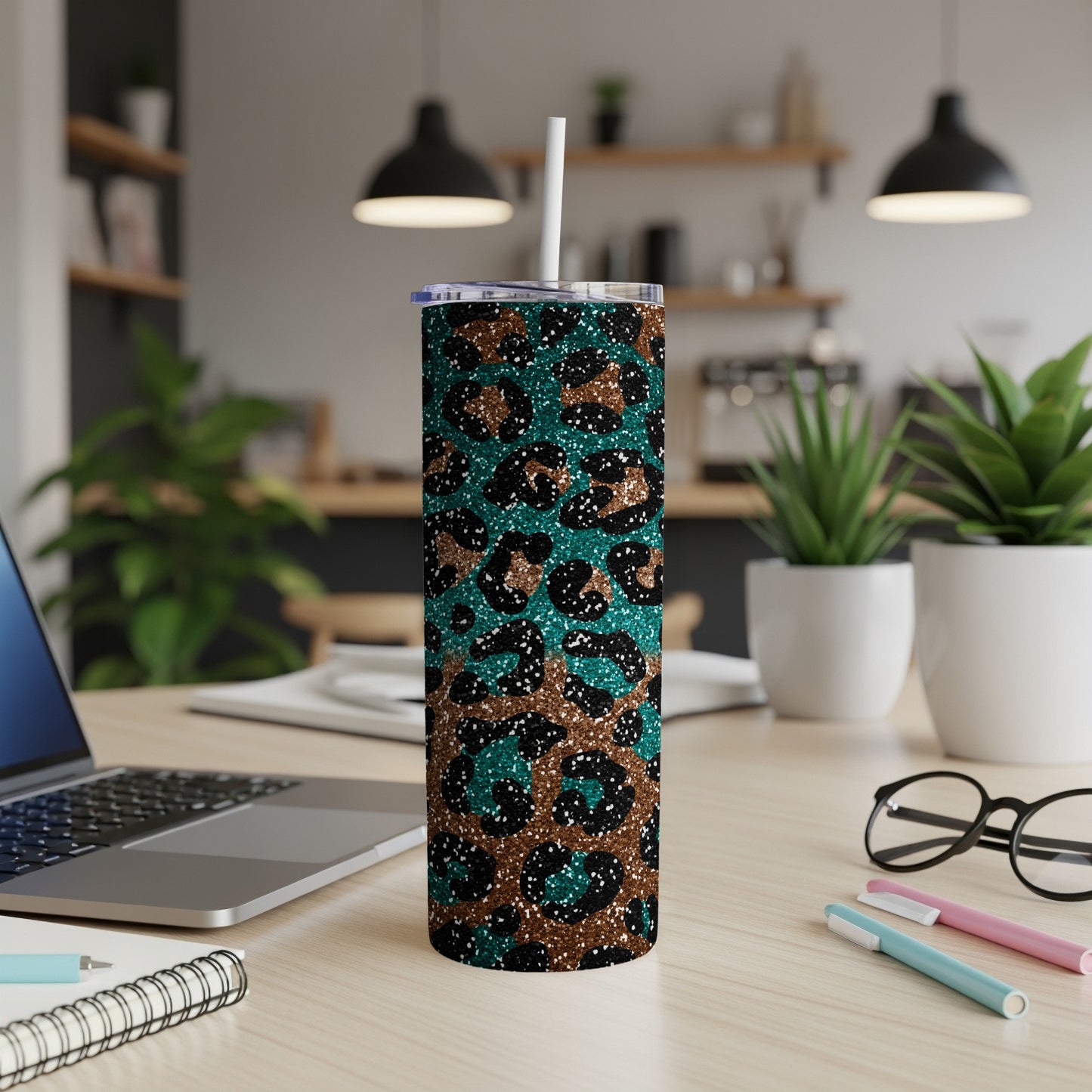 Teal and brown glitter leopard print tumbler with white straw on desk.