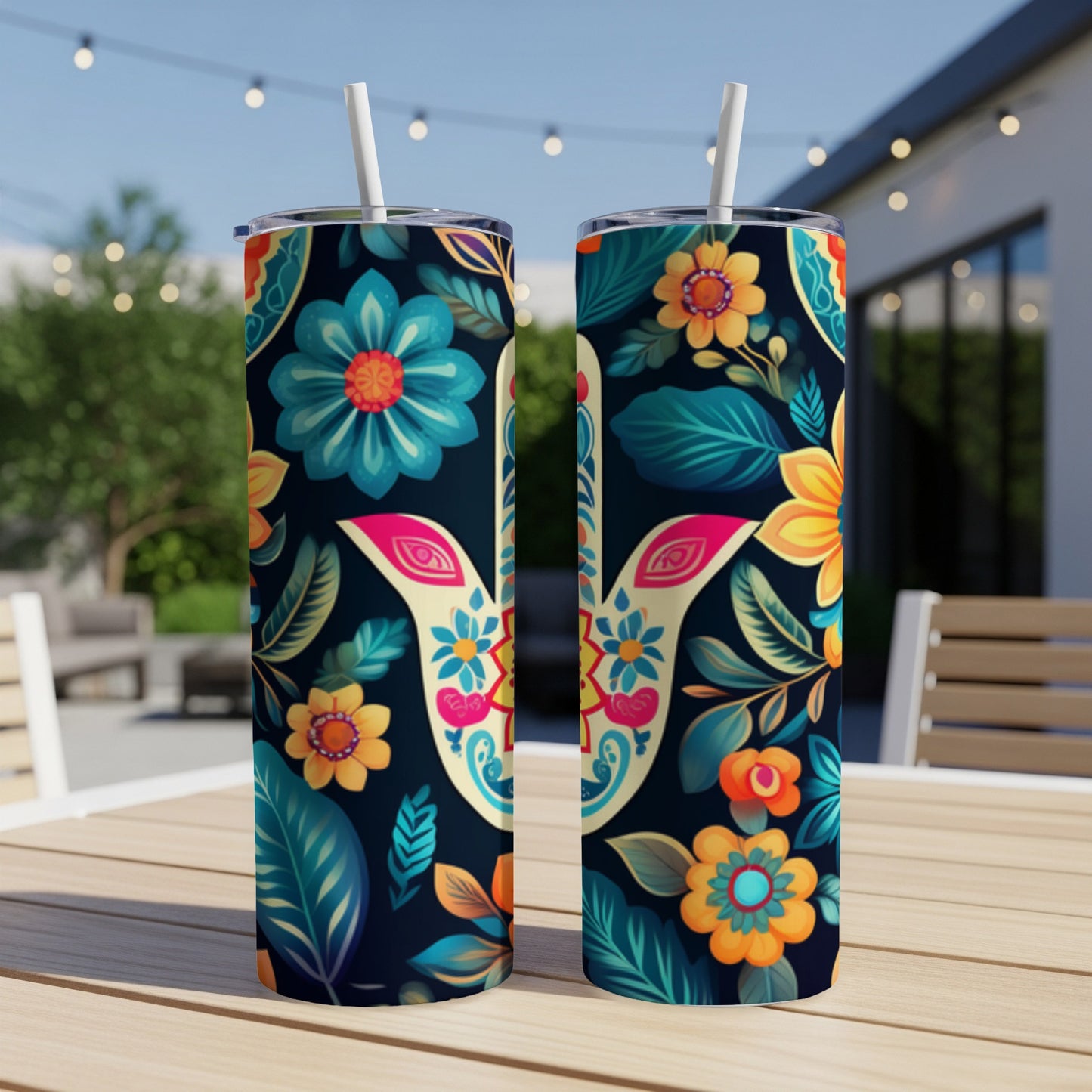 Two colorful floral pattern tumblers with straws on a wooden table.