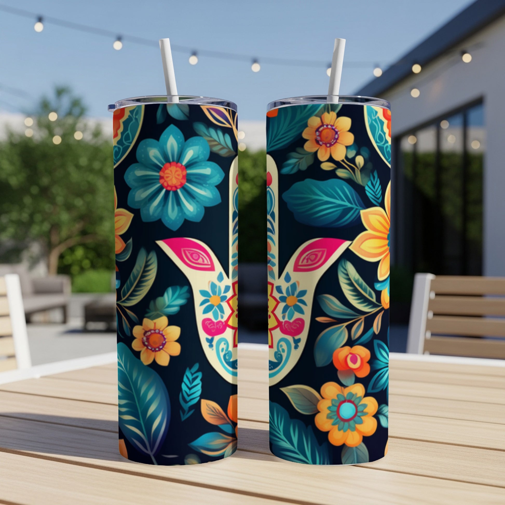 Two colorful floral pattern tumblers with straws on a wooden table.