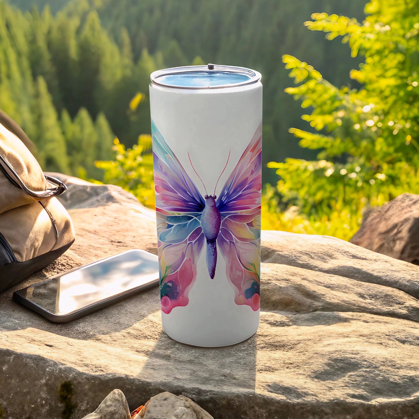 White tumbler with a colorful butterfly design, placed outdoors on rocks.
