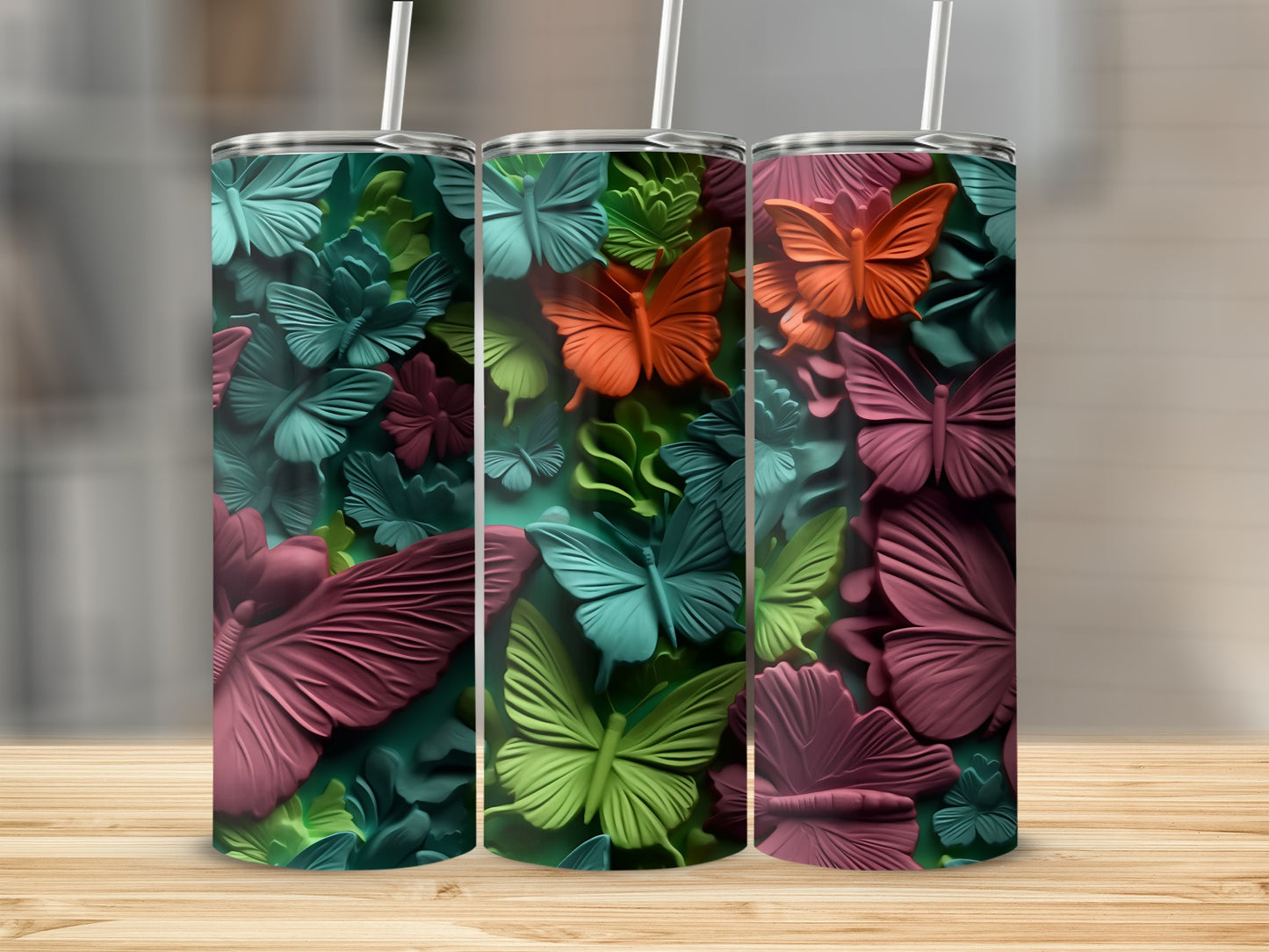 Three tumblers with embossed butterfly designs in shades of teal, green, and pink.
