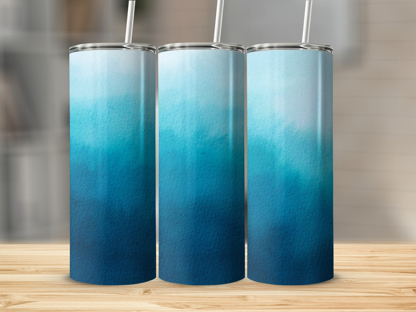 Three tumblers with a blue watercolor ombre design and straws.