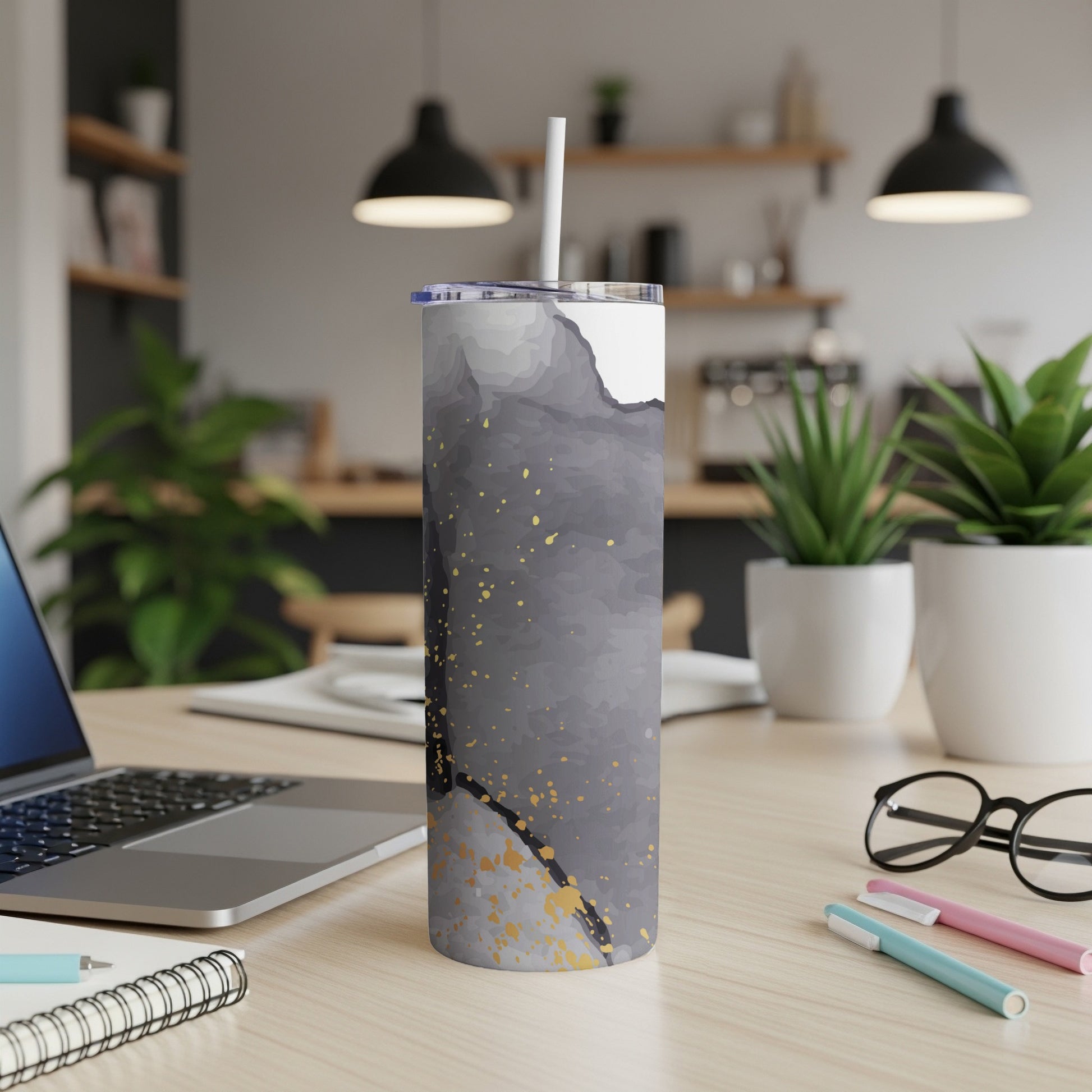 Gray and gold abstract watercolor tumbler with straw on desk.