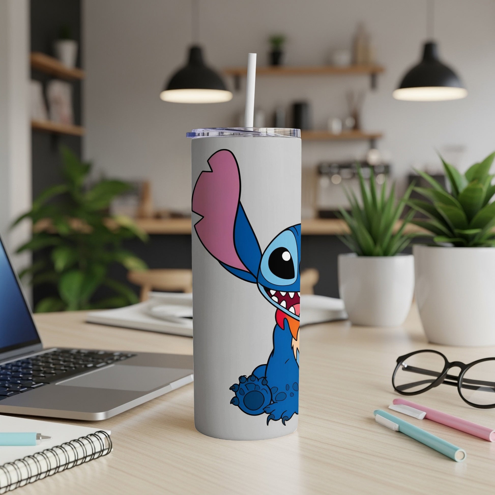 Stitch character on a gray tumbler with a straw, on a desk.