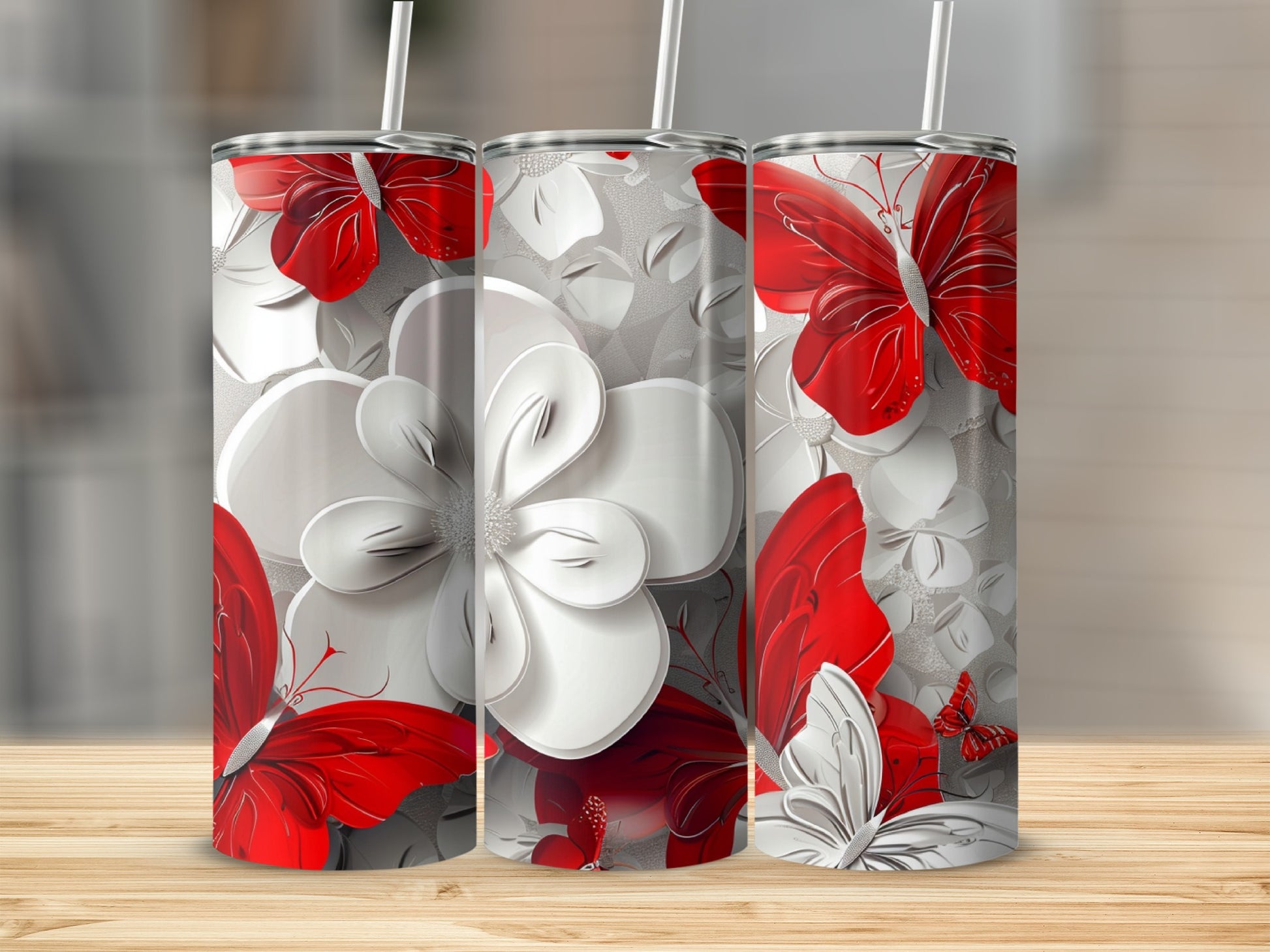 Three floral tumblers with red butterfly accents on a wooden surface.