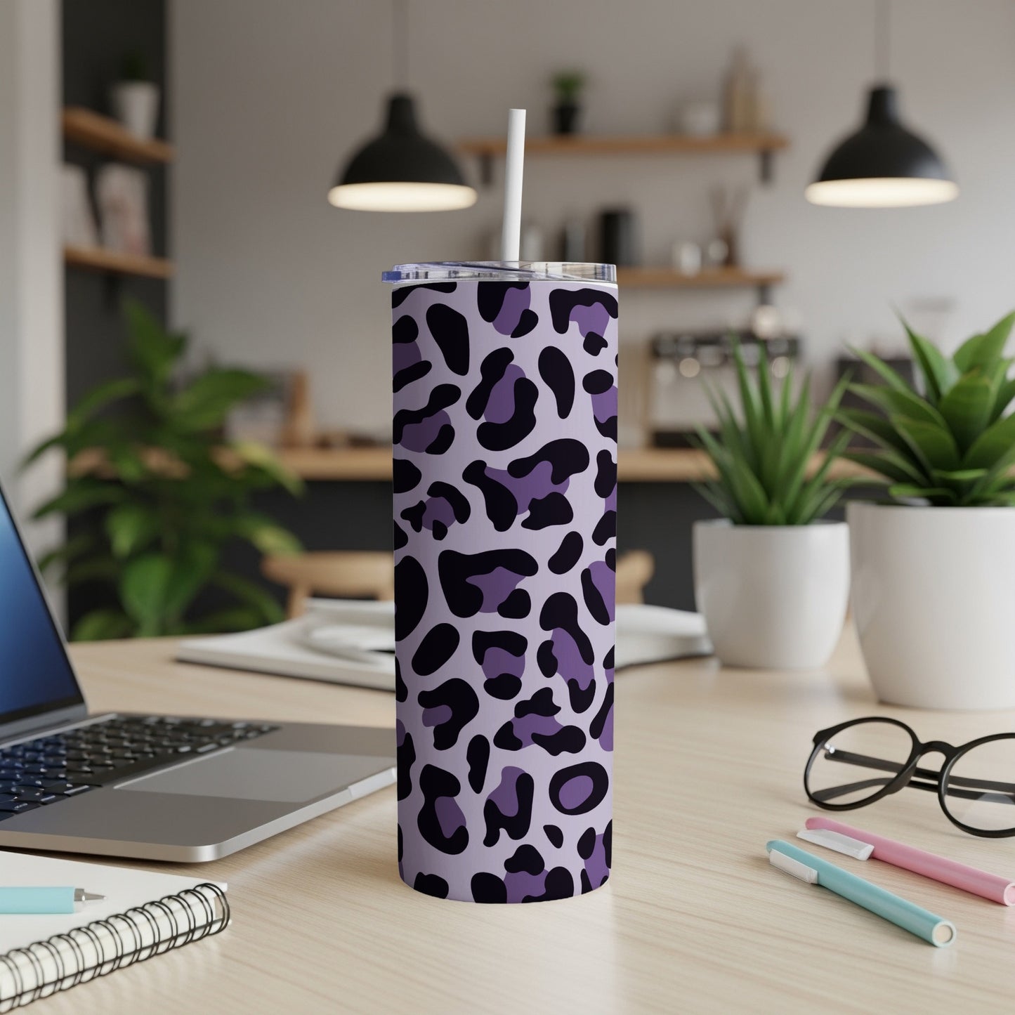 Purple and black leopard print tumbler with straw on a desk.